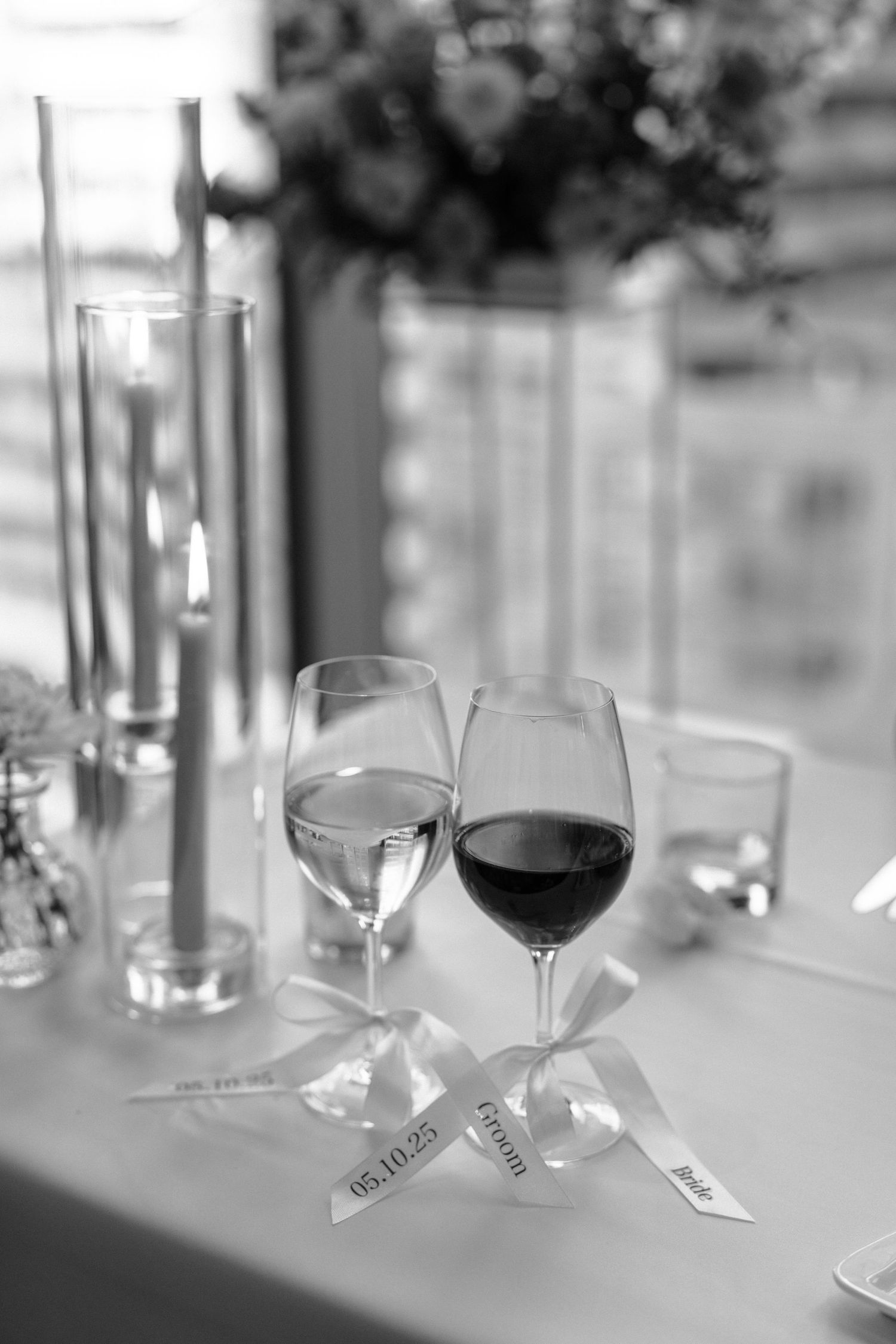 Elegant table setting with red and white wine glasses decorated with ribbons and lit candles in black and white.