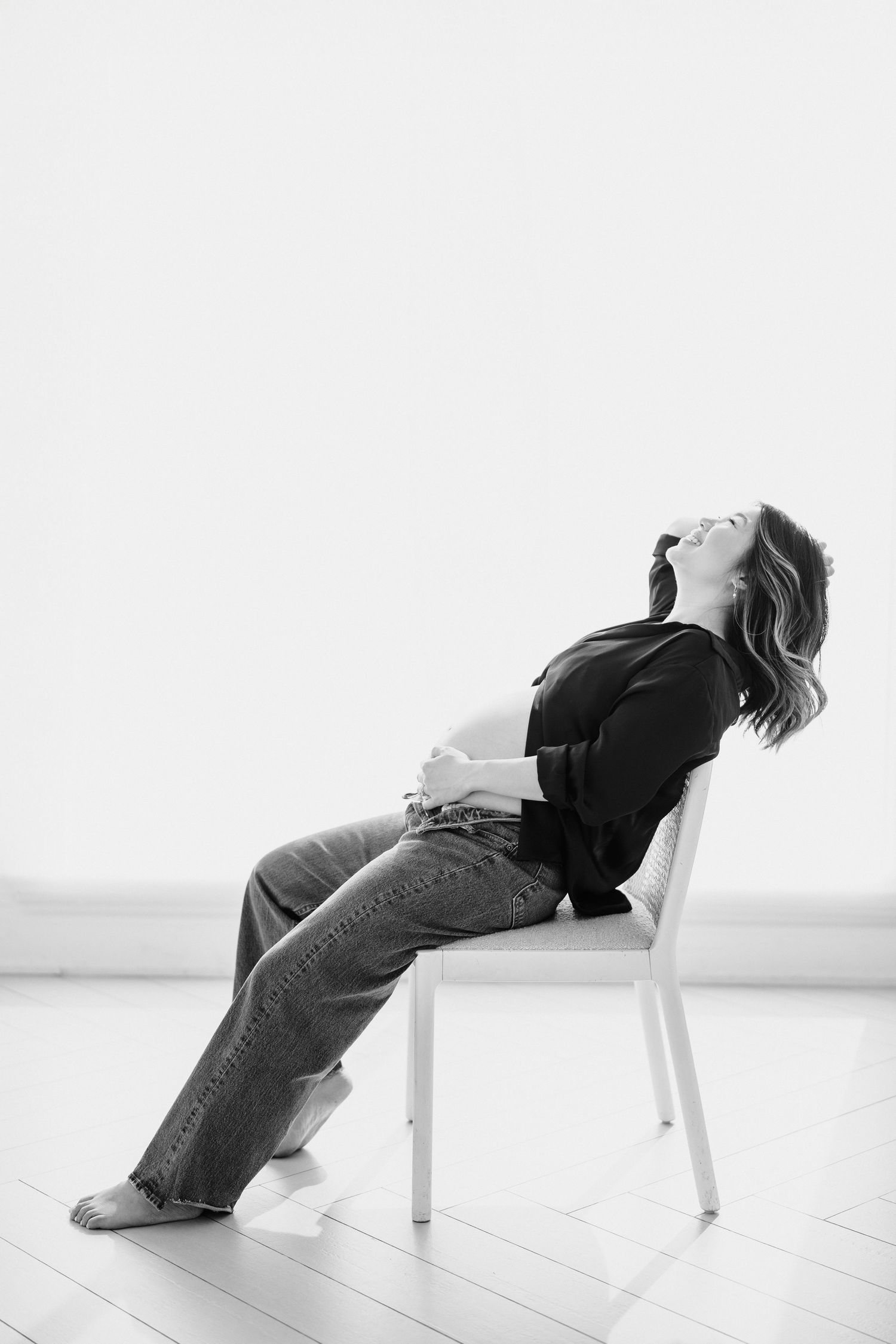 Black and white artistic series showing person reclining backwards in white chair against minimal background.