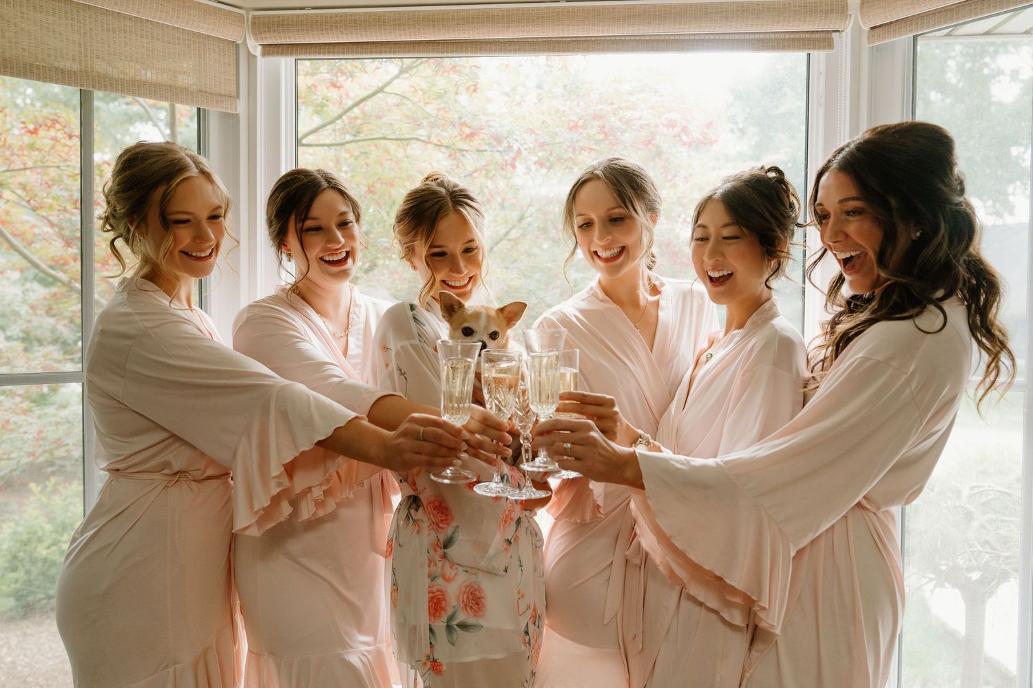 A group wearing matching white robes toasts with champagne glasses during a celebratory gathering.