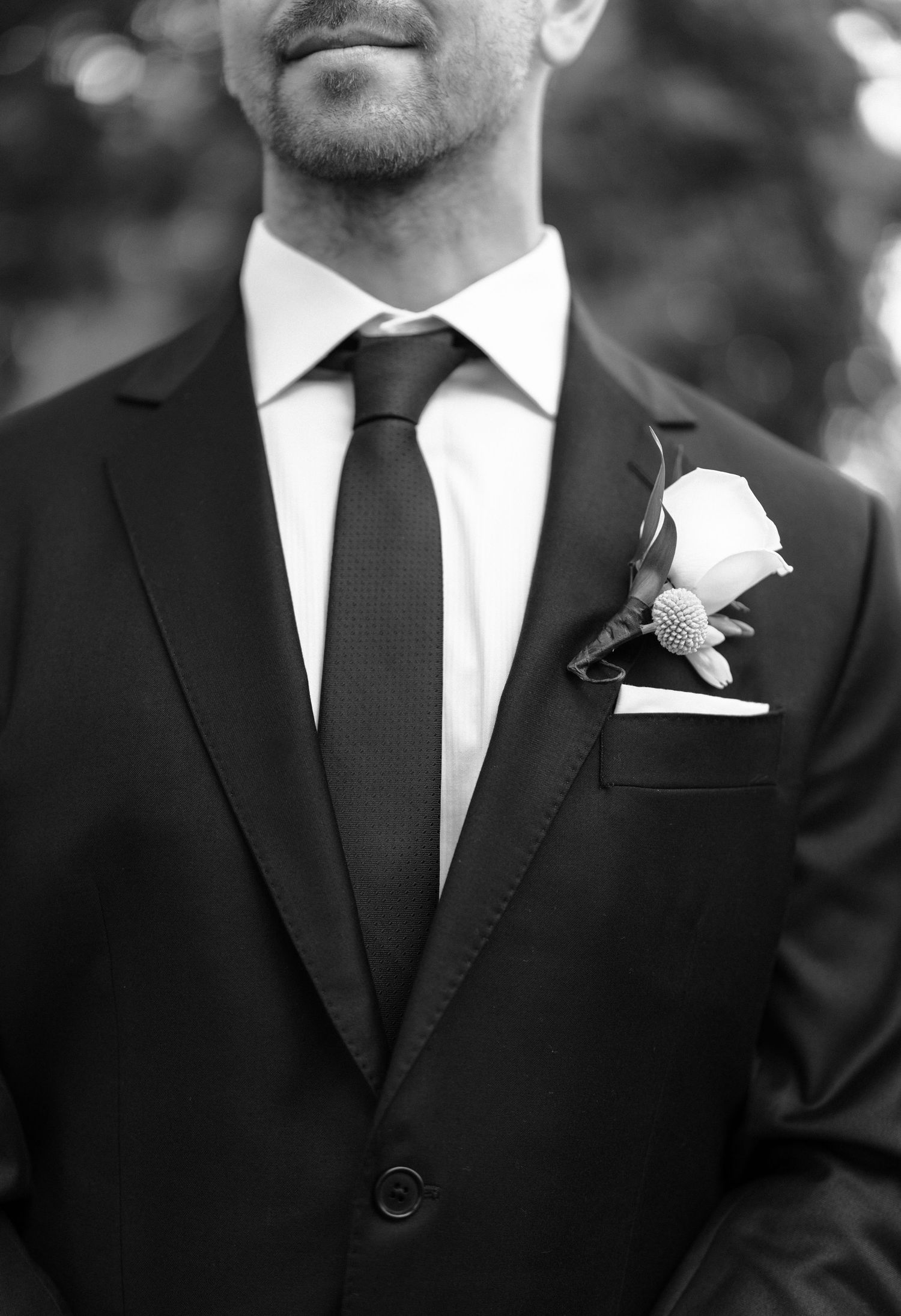 Black and white photo showing groomsmen in classic black suits with white boutonnieres.