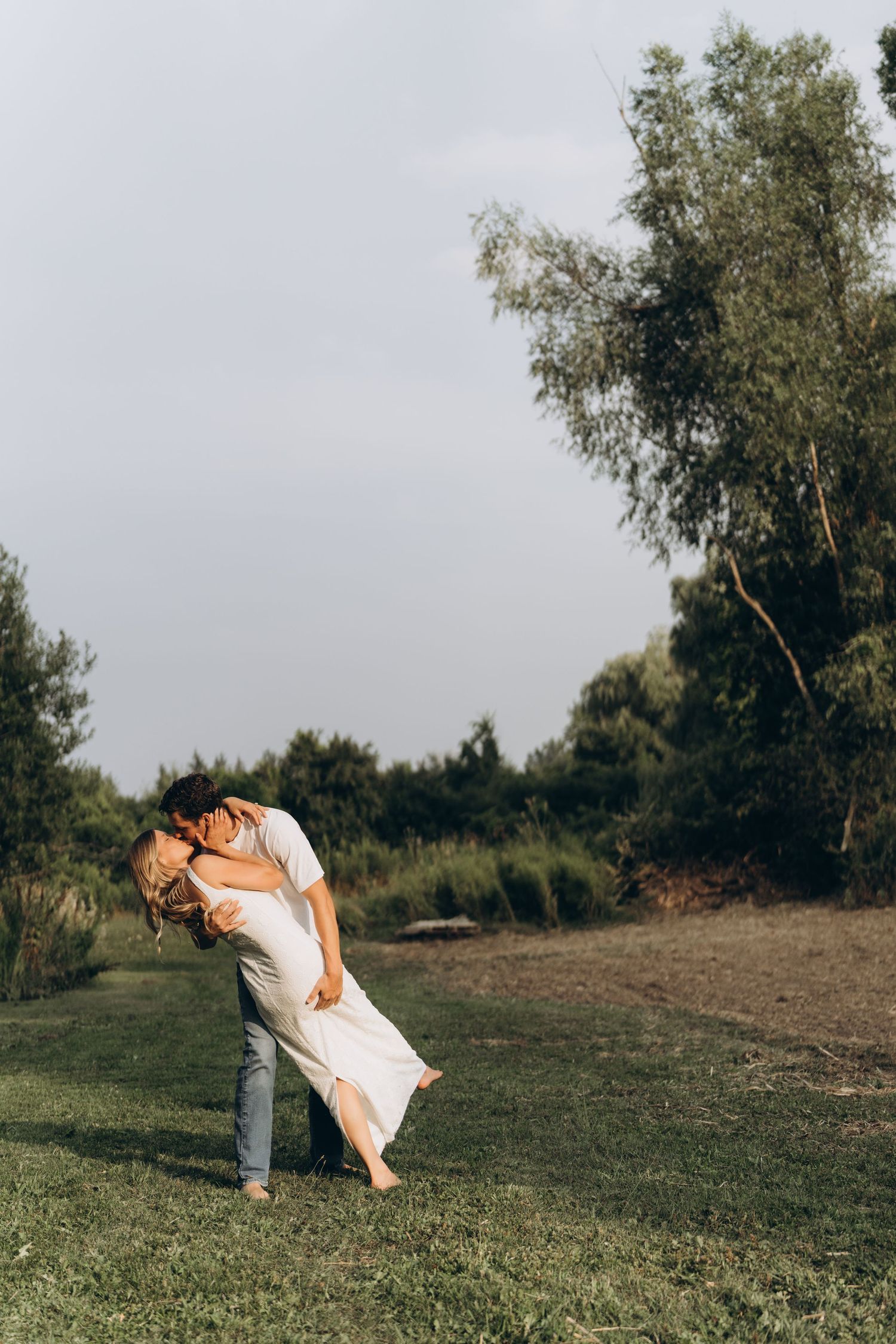 A sequence of three artistic photos showing a person in white dress dancing and twirling gracefully on a grassy hillside.