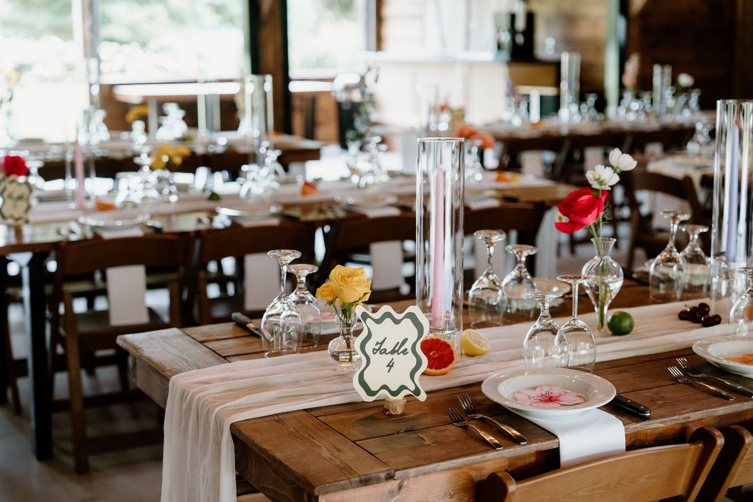 Rustic wooden tables and benches set up for an elegant wedding reception with white table settings and floral centerpieces.