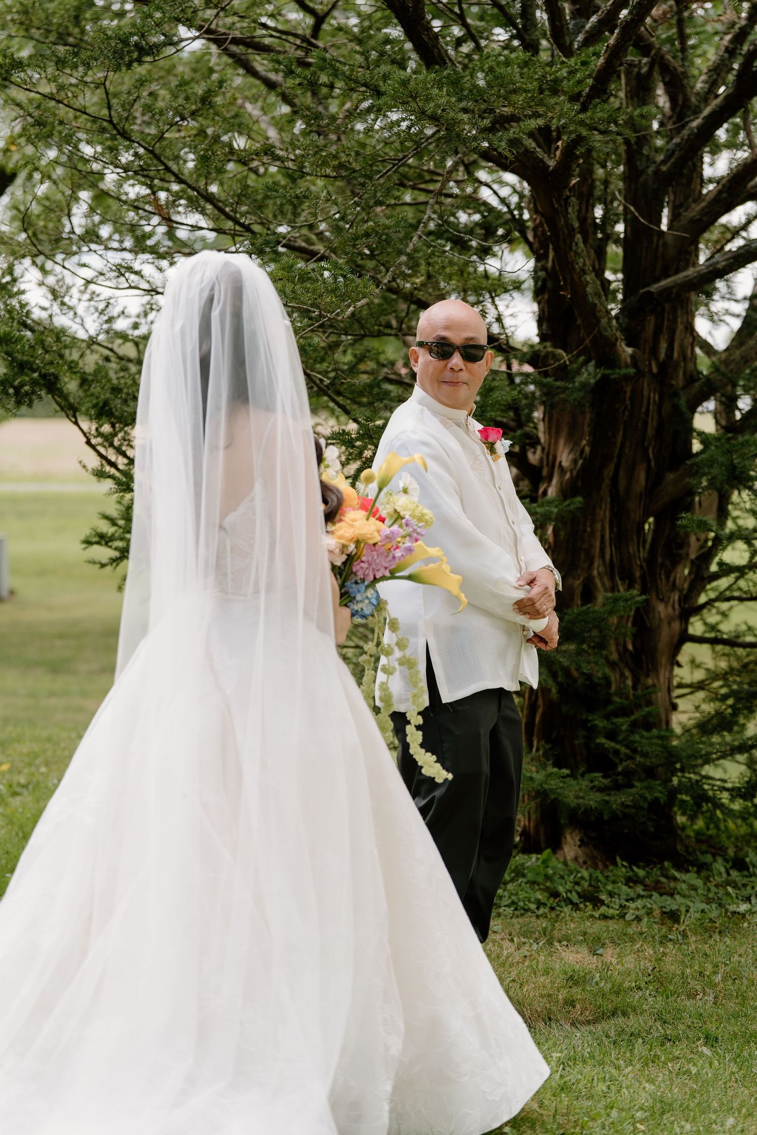 A sequence of first look wedding photos showing a bride and groom meeting in a lush garden setting with flowing white veil.