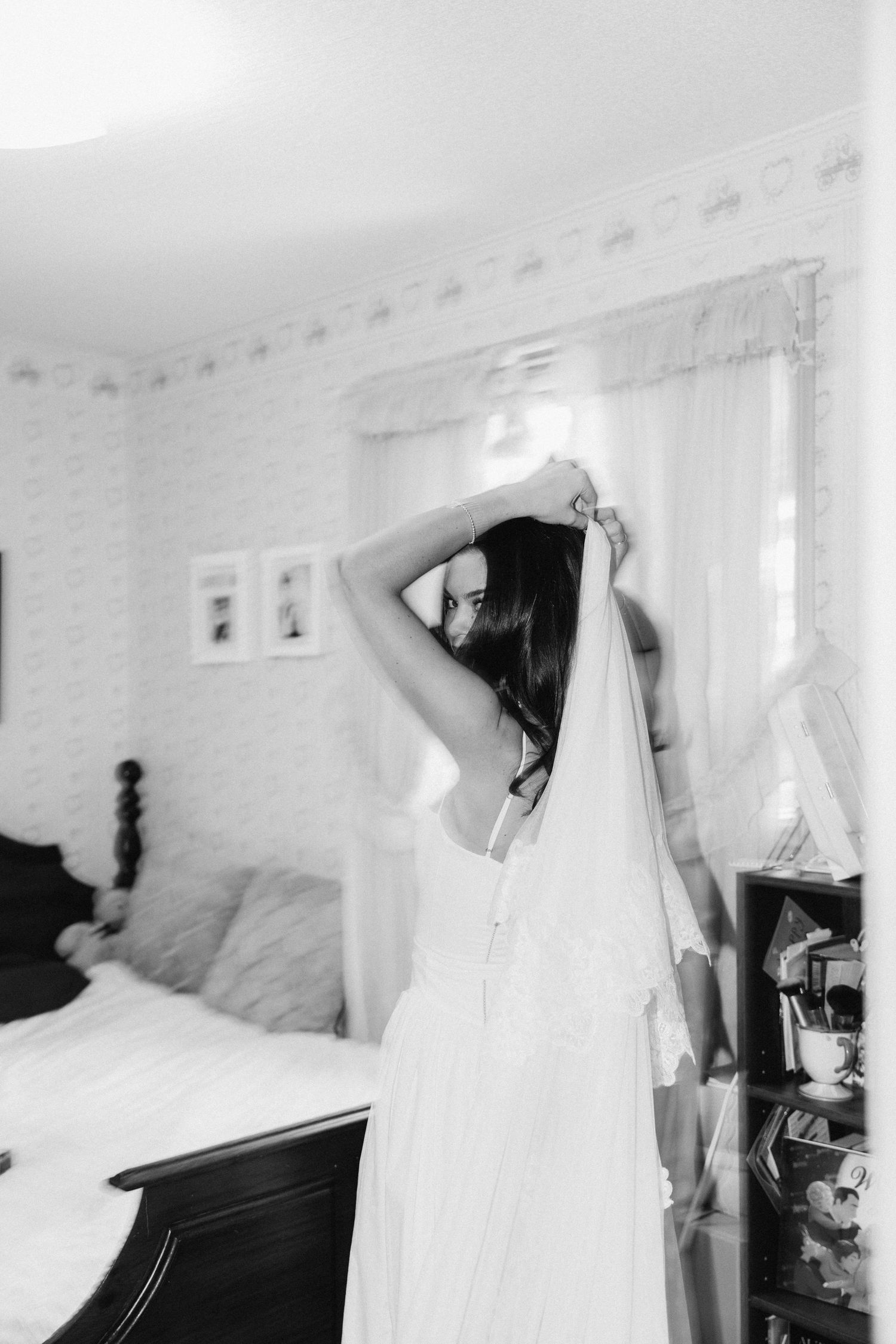 Black and white bridal preparation sequence showing a woman getting dressed in a flowing white wedding veil and gown.