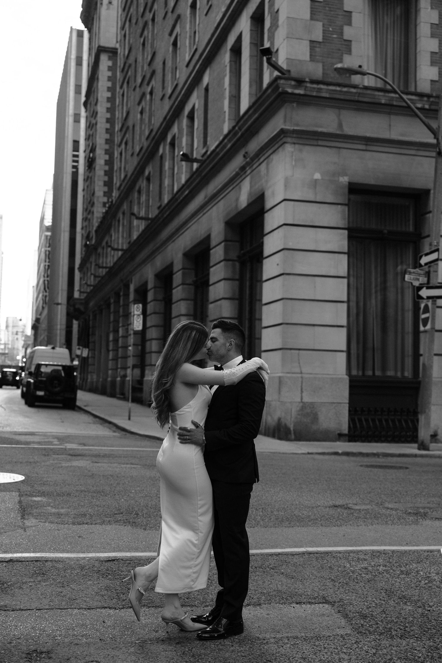 Two people dance together in an intimate black and white moment on an urban street corner.