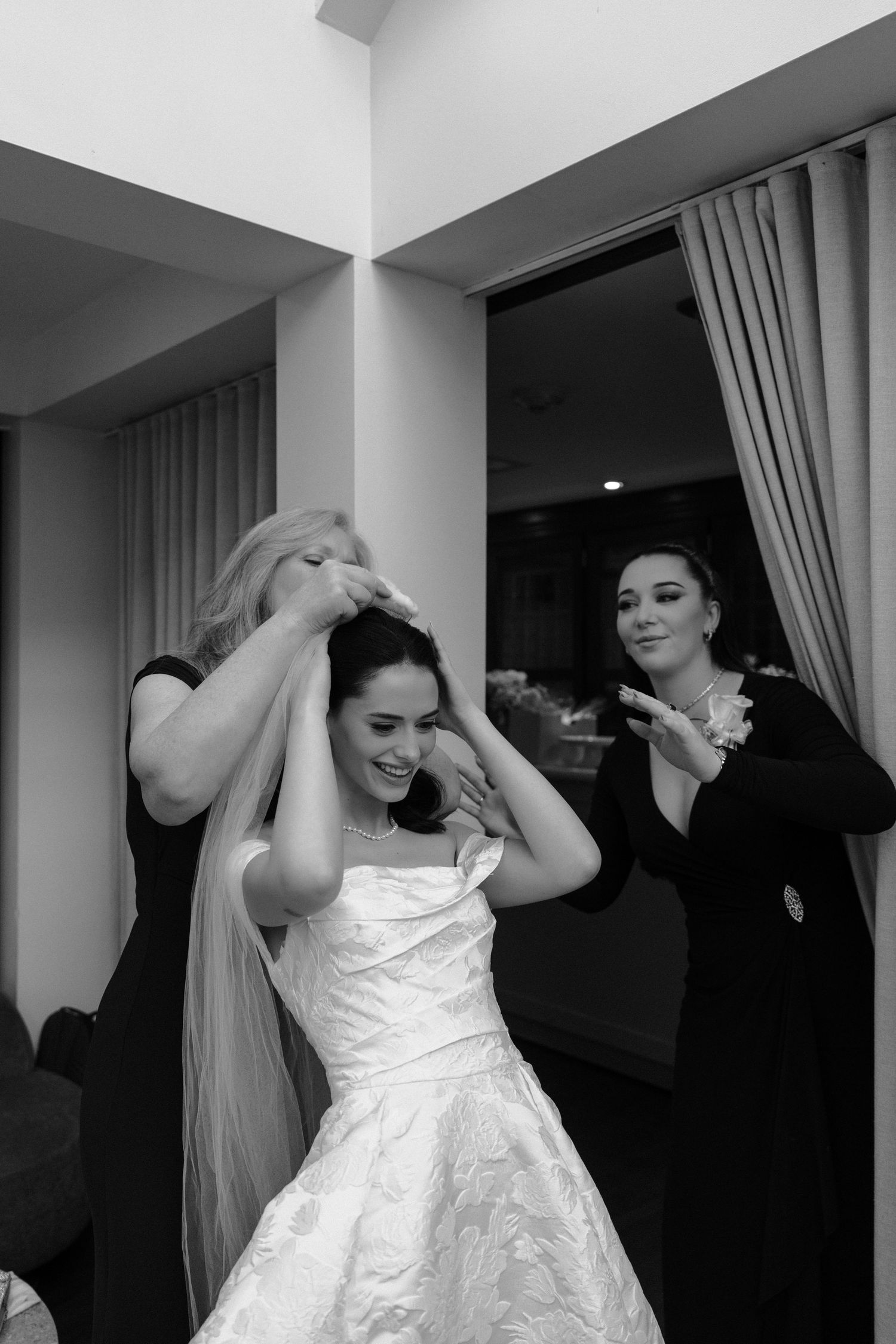 A sequence of black and white photos showing someone putting on a white wedding dress.