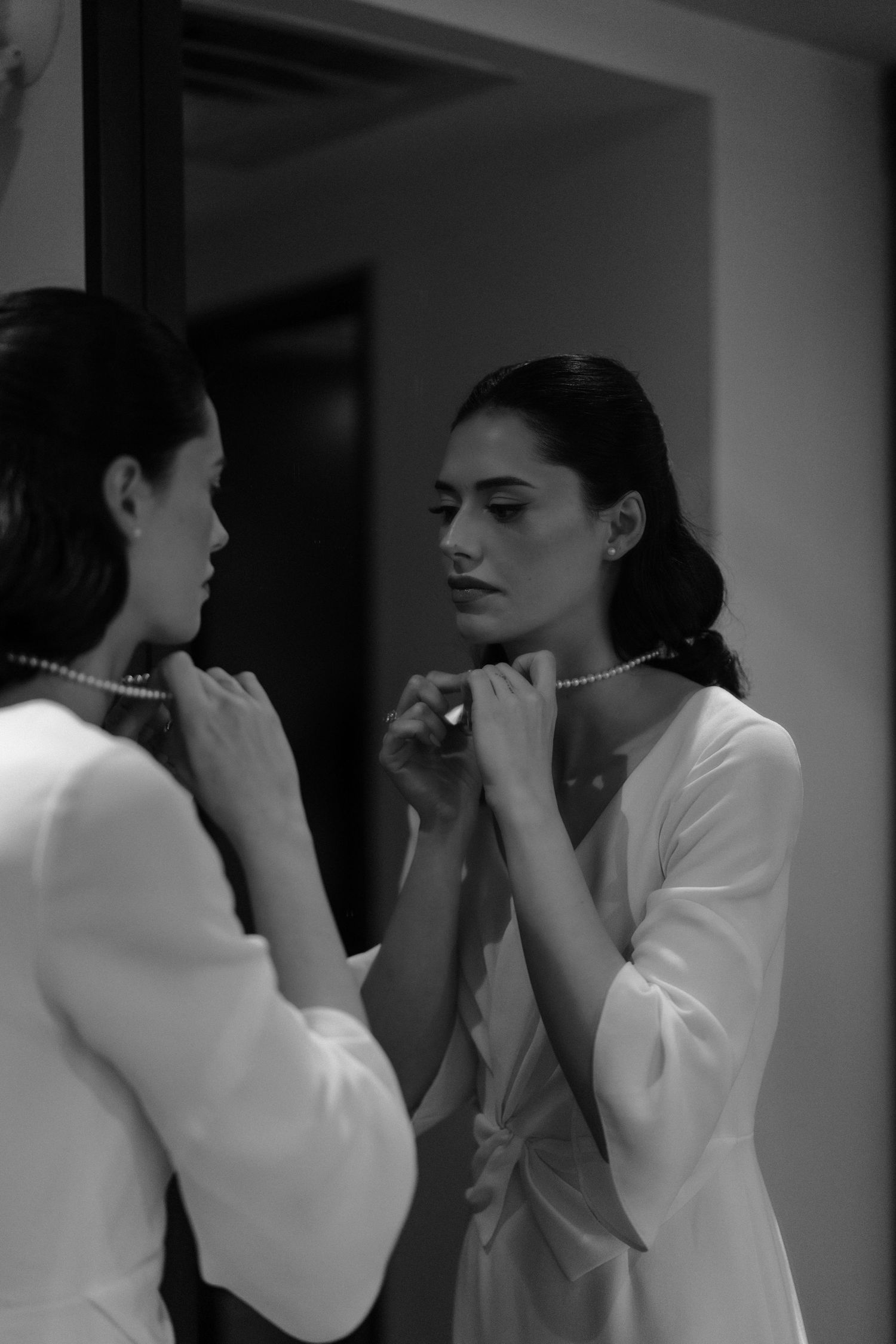 A sequence of black and white photos showing two people in white clothing facing each other in an intimate conversation.