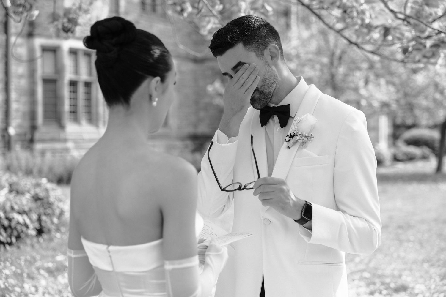 Emotional black and white wedding moment as couple shares intimate first look in garden setting.