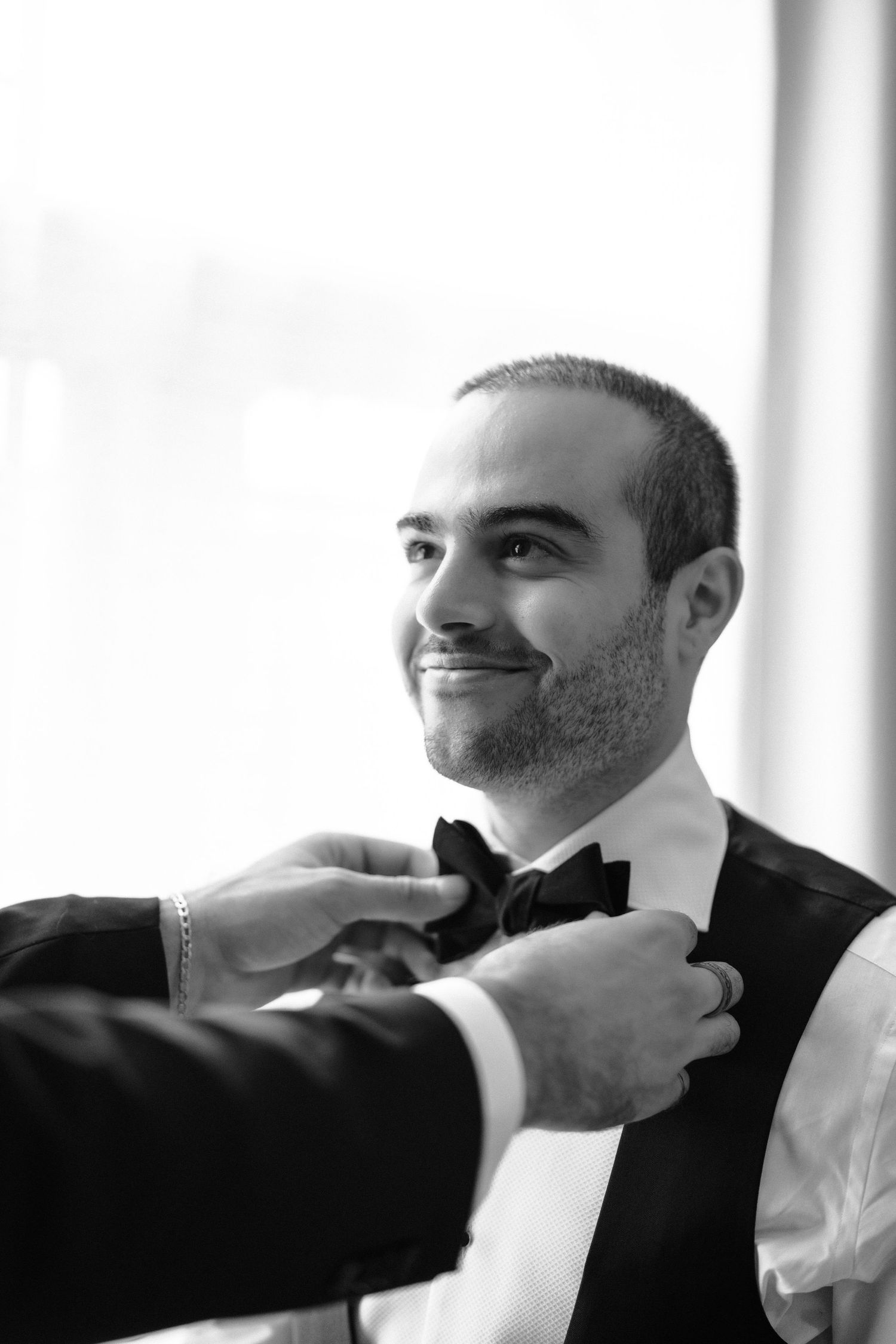 Black and white photo series showing someone adjusting their bowtie while getting dressed in formal attire.
