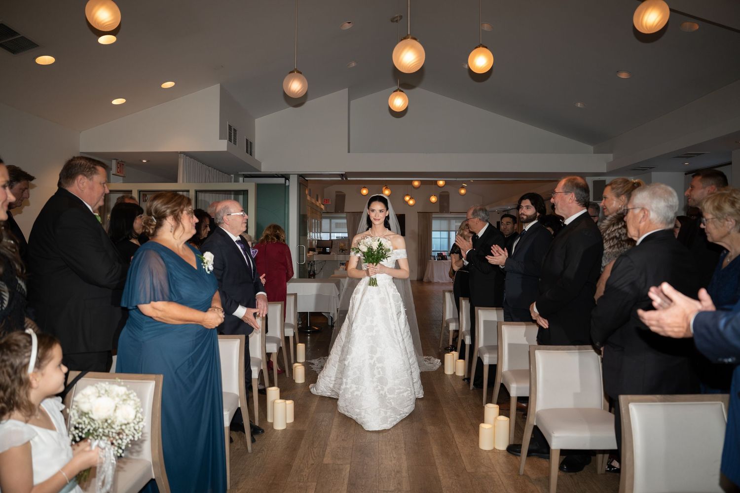 Wedding reception venue decorated with warm glowing pendant lights and tables set for an elegant celebration.