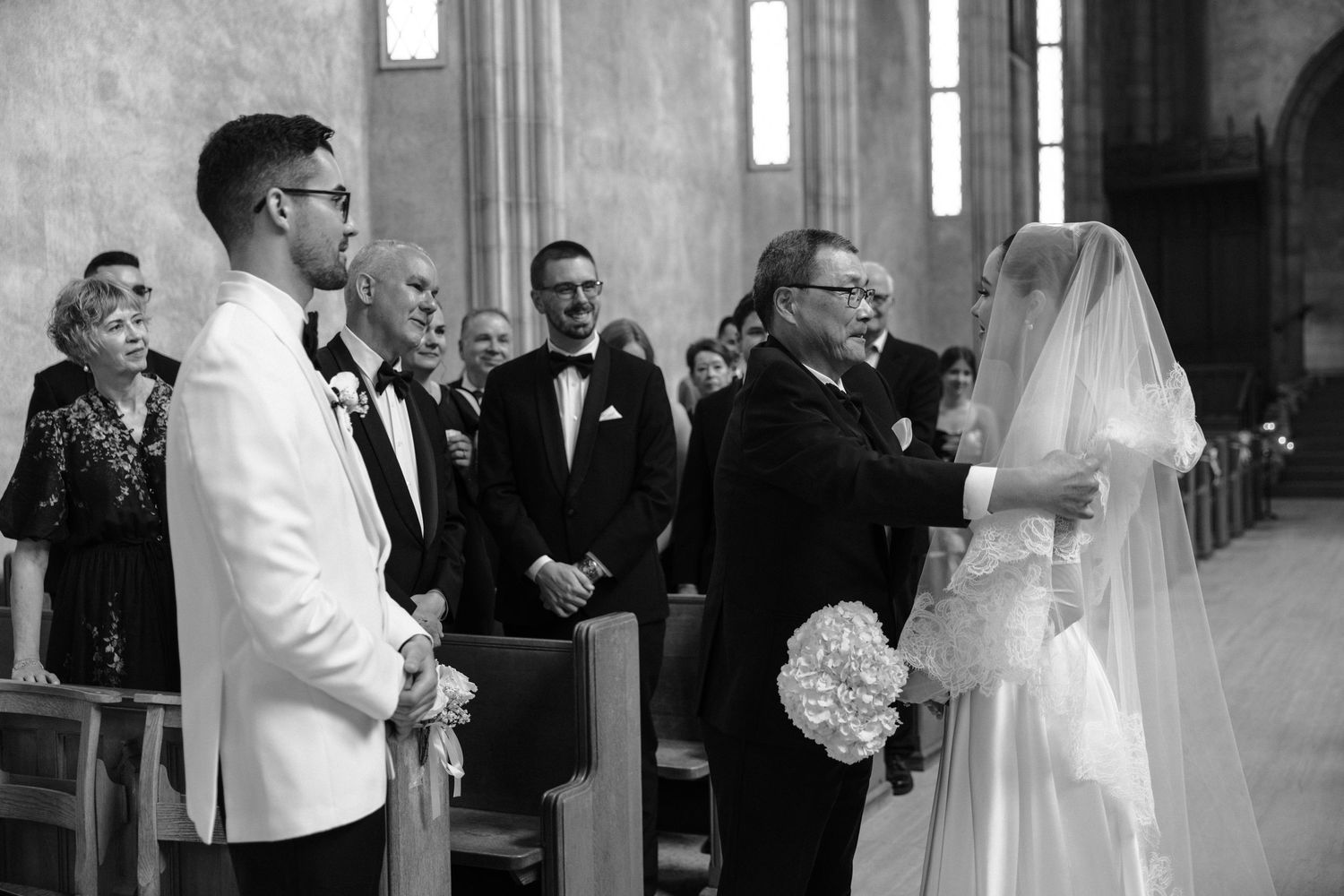A joyful wedding ceremony moment captured in black and white with the couple celebrating in a church setting.