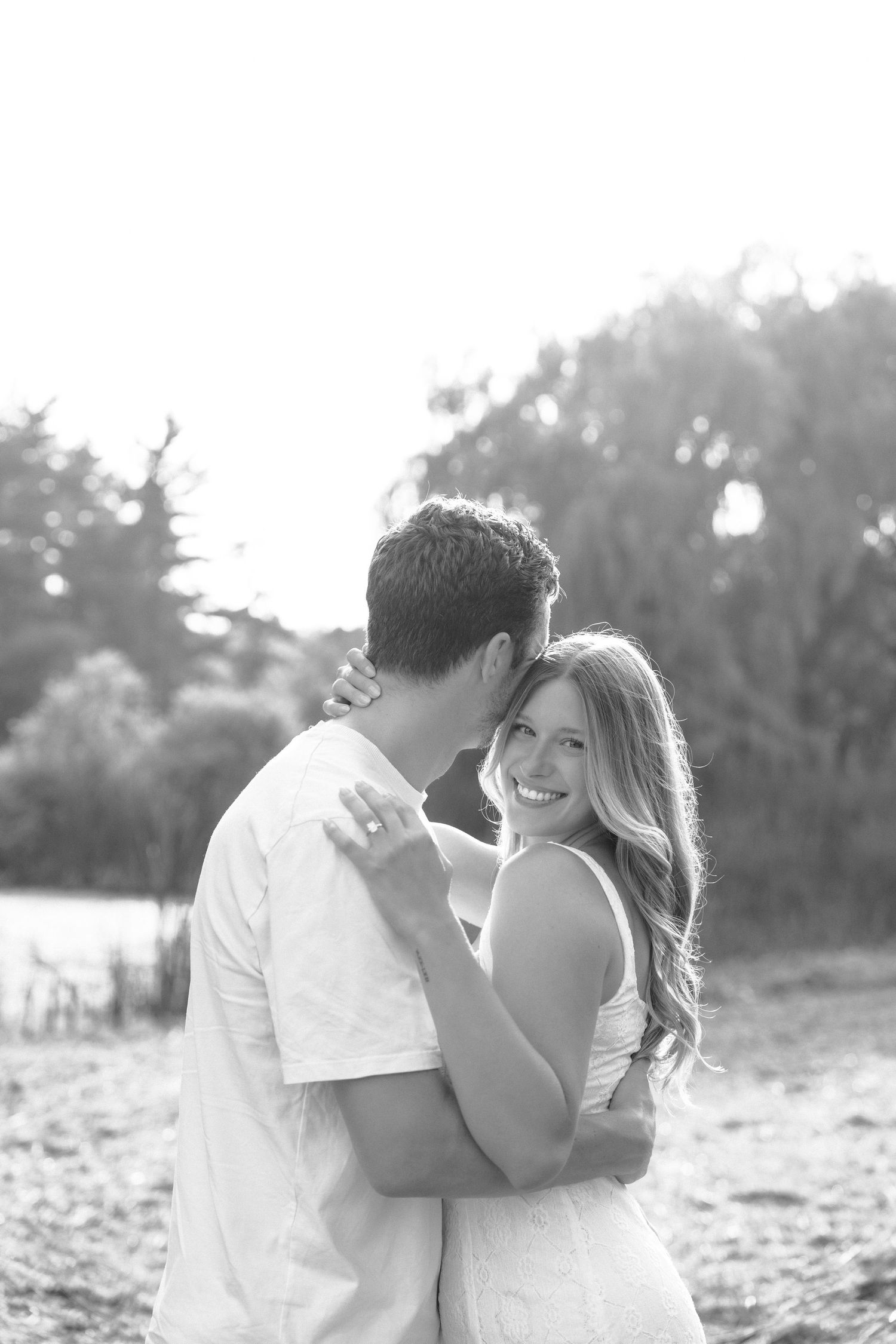A romantic black and white photo series showing a couple embracing on a sunny beach.