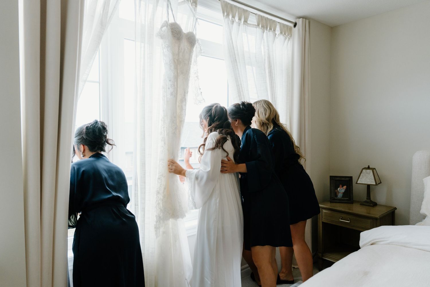 Panoramic view of a bright reception room with people gathered near white curtained windows.