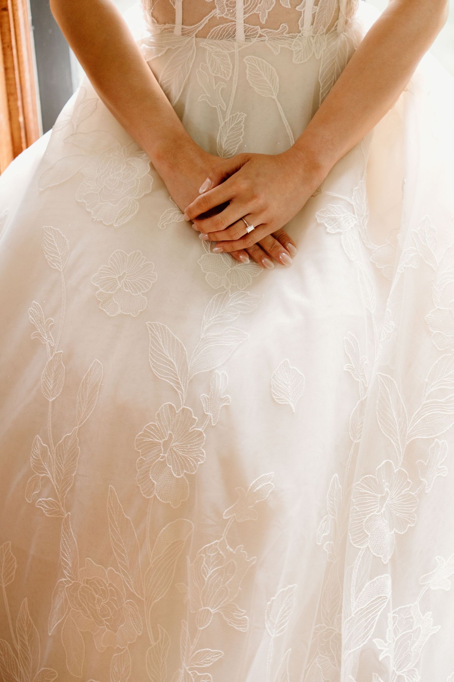 Close up details of an embroidered white wedding dress with delicate floral patterns.