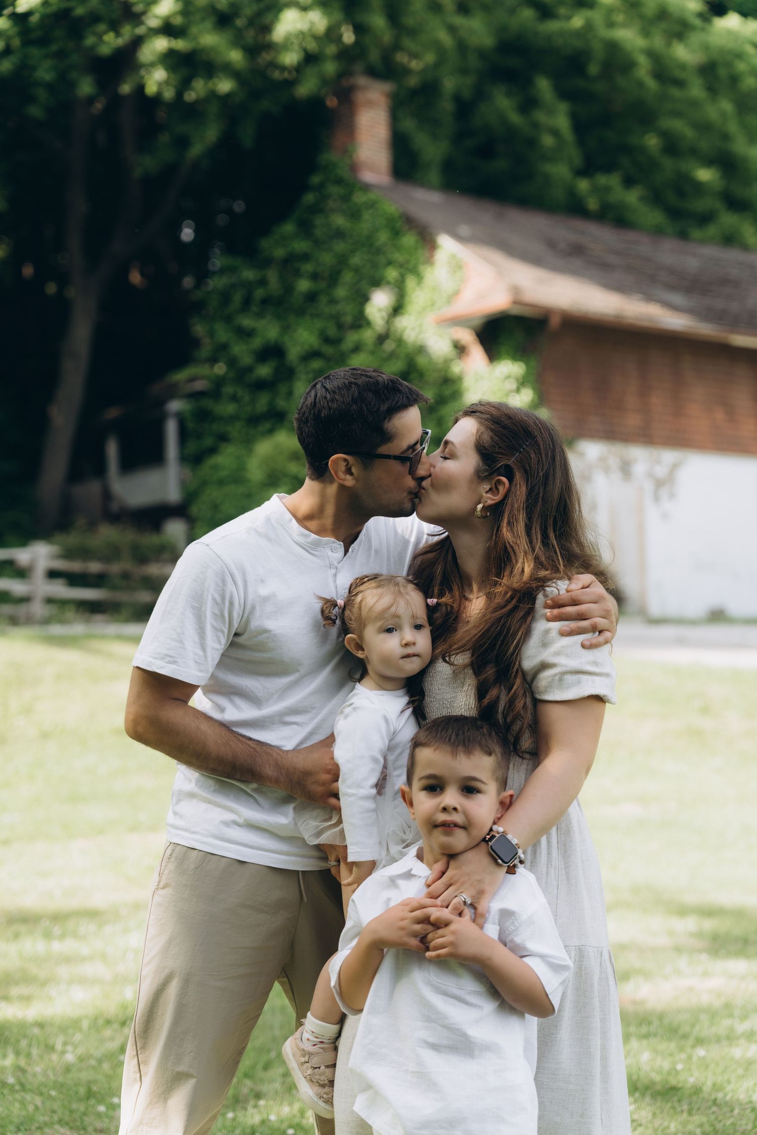 A happy family sharing an intimate moment while standing together outdoors in front of a rustic building.