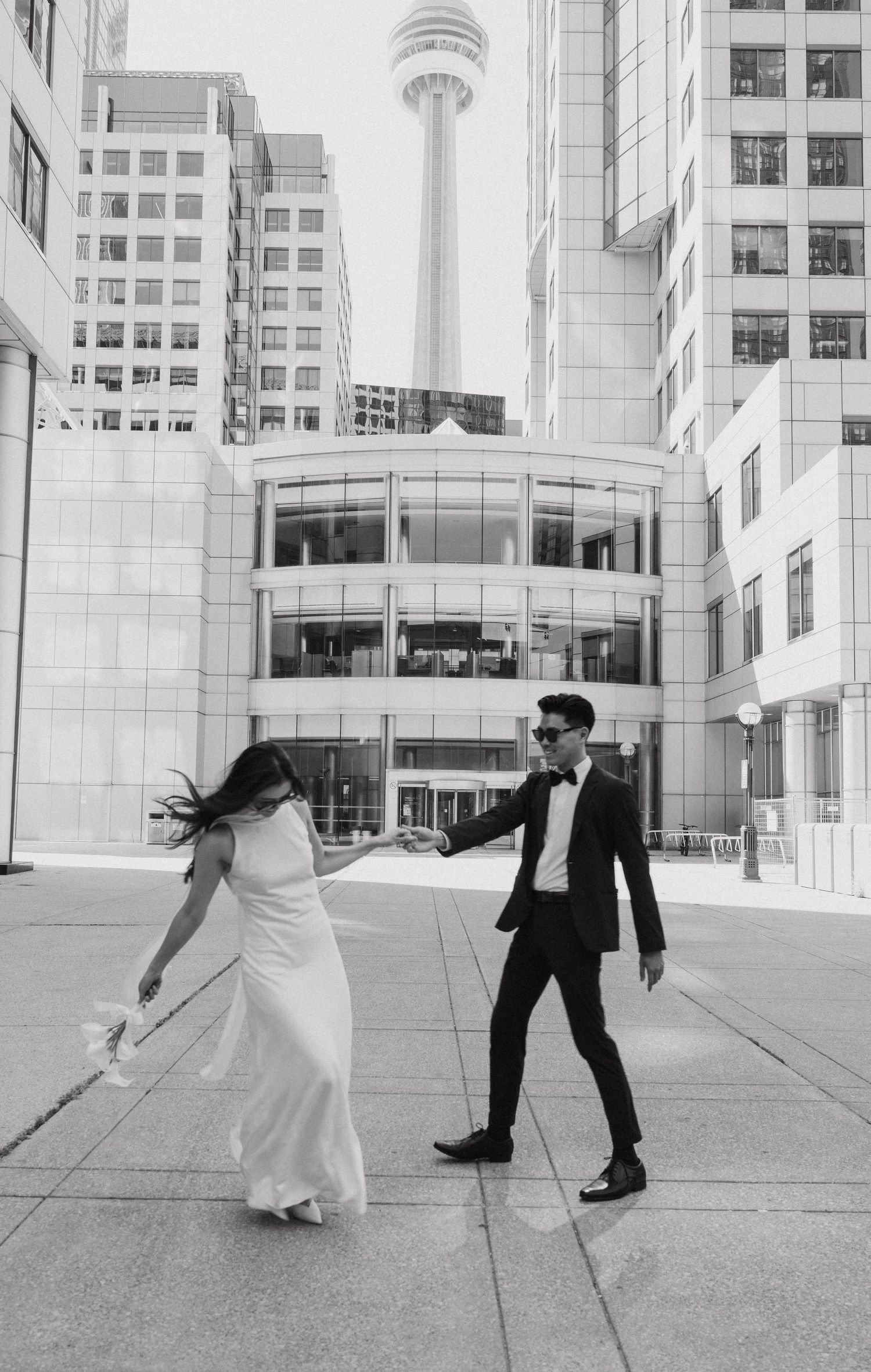 Black and white photos show a couple dancing and twirling in front of modern architecture.