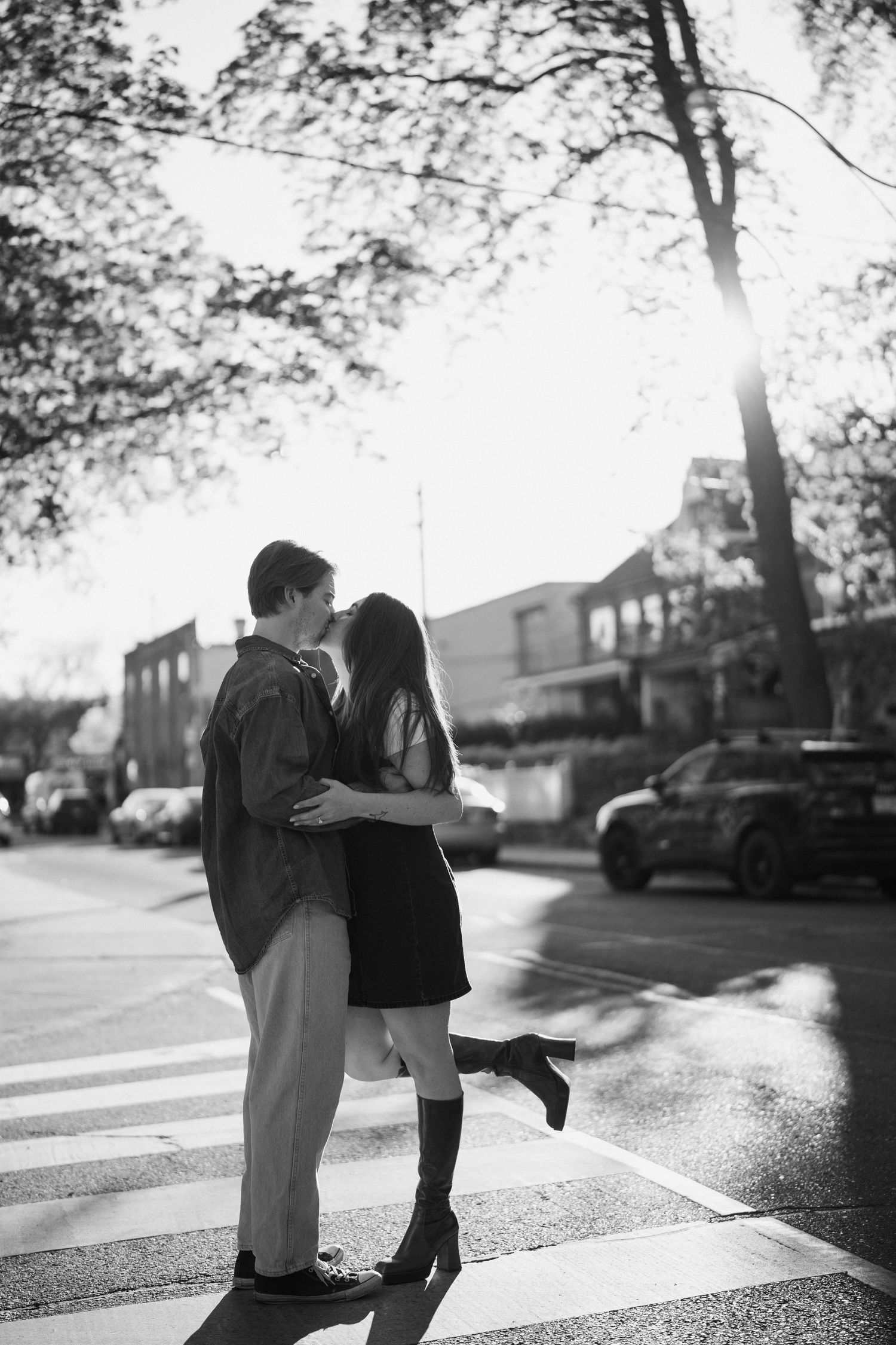 A stylish couple sharing an intimate moment on a crosswalk in black and white photography.