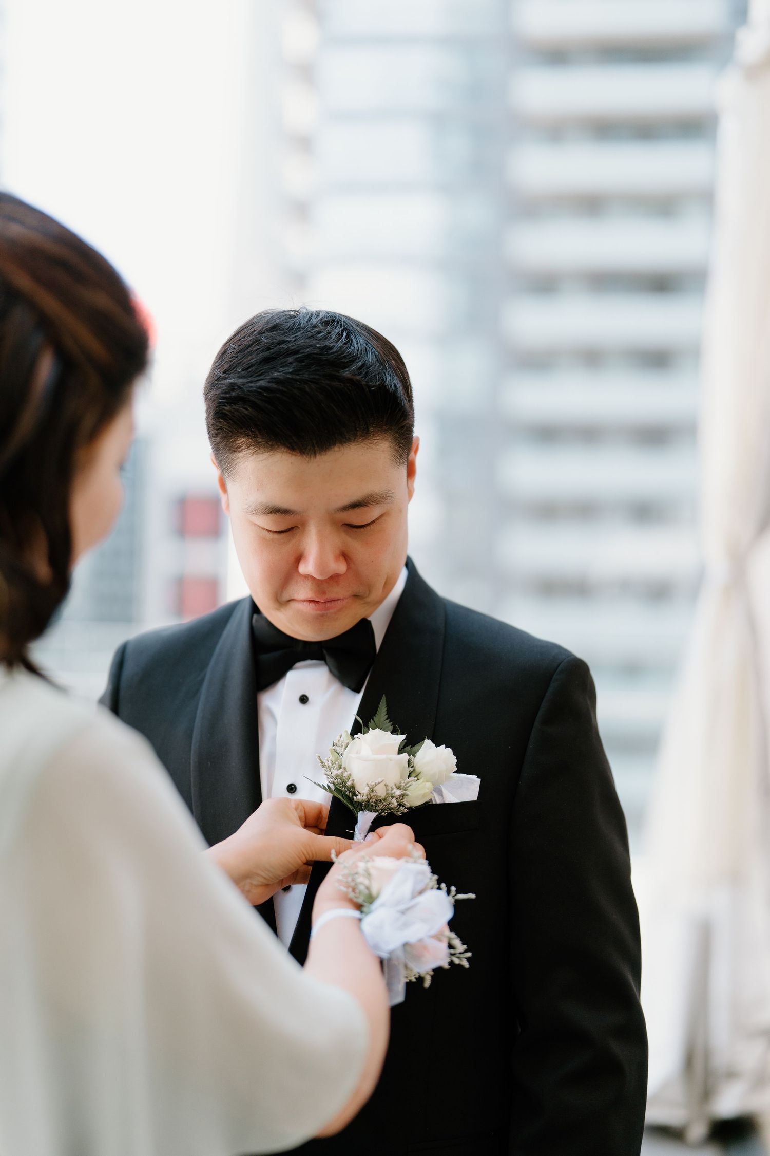A joyful couple shares a tender moment during their wedding ceremony with white flower bouquet and black attire.