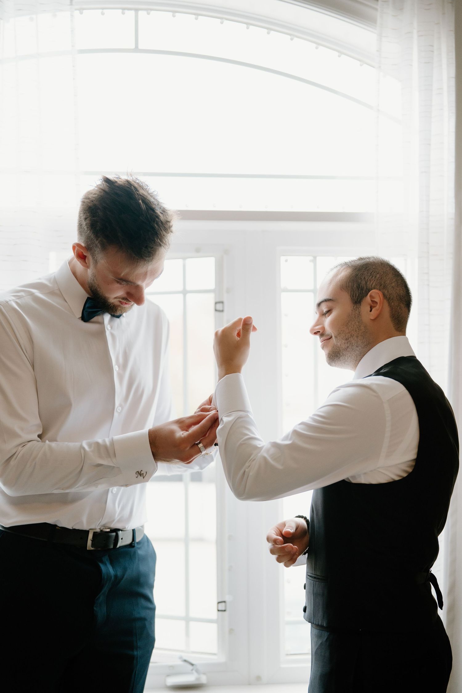 A sequence of photos showing two men in formal attire adjusting their outfits against a bright white background.