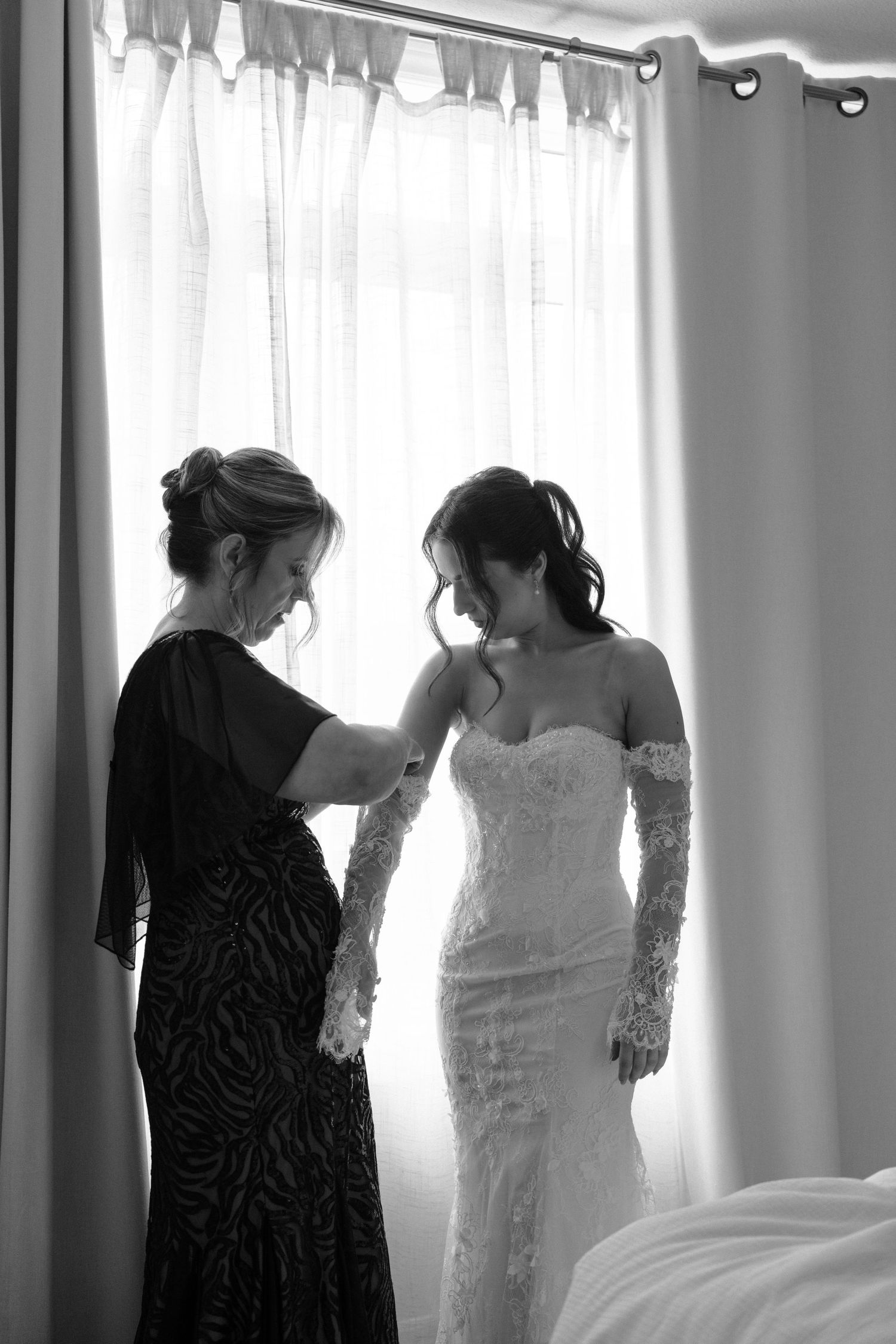 A series of black and white photos showing a bride getting ready with help from another person in silhouette.