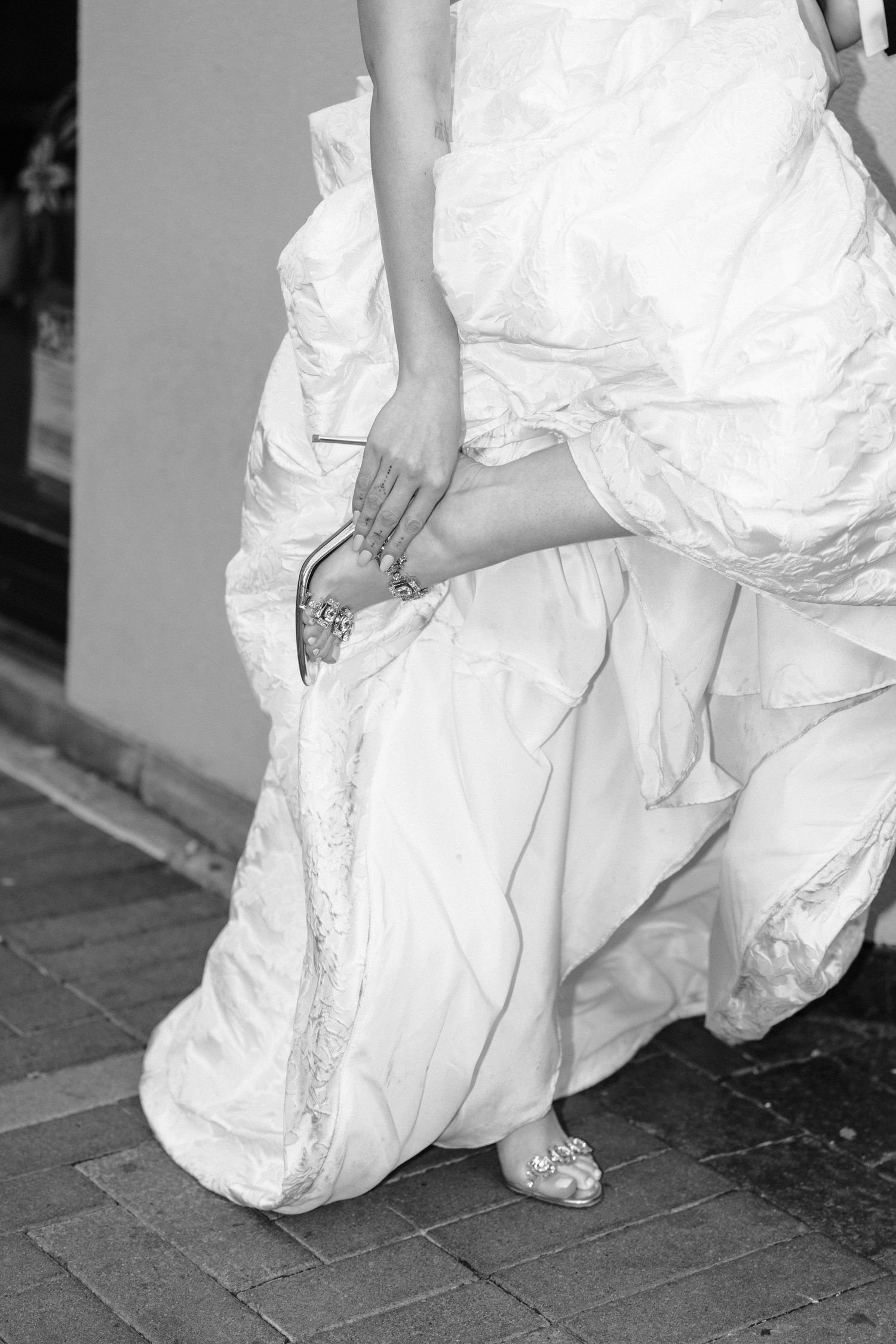 Close-up shots of a white wedding dress and shoes against a brick paved walkway.