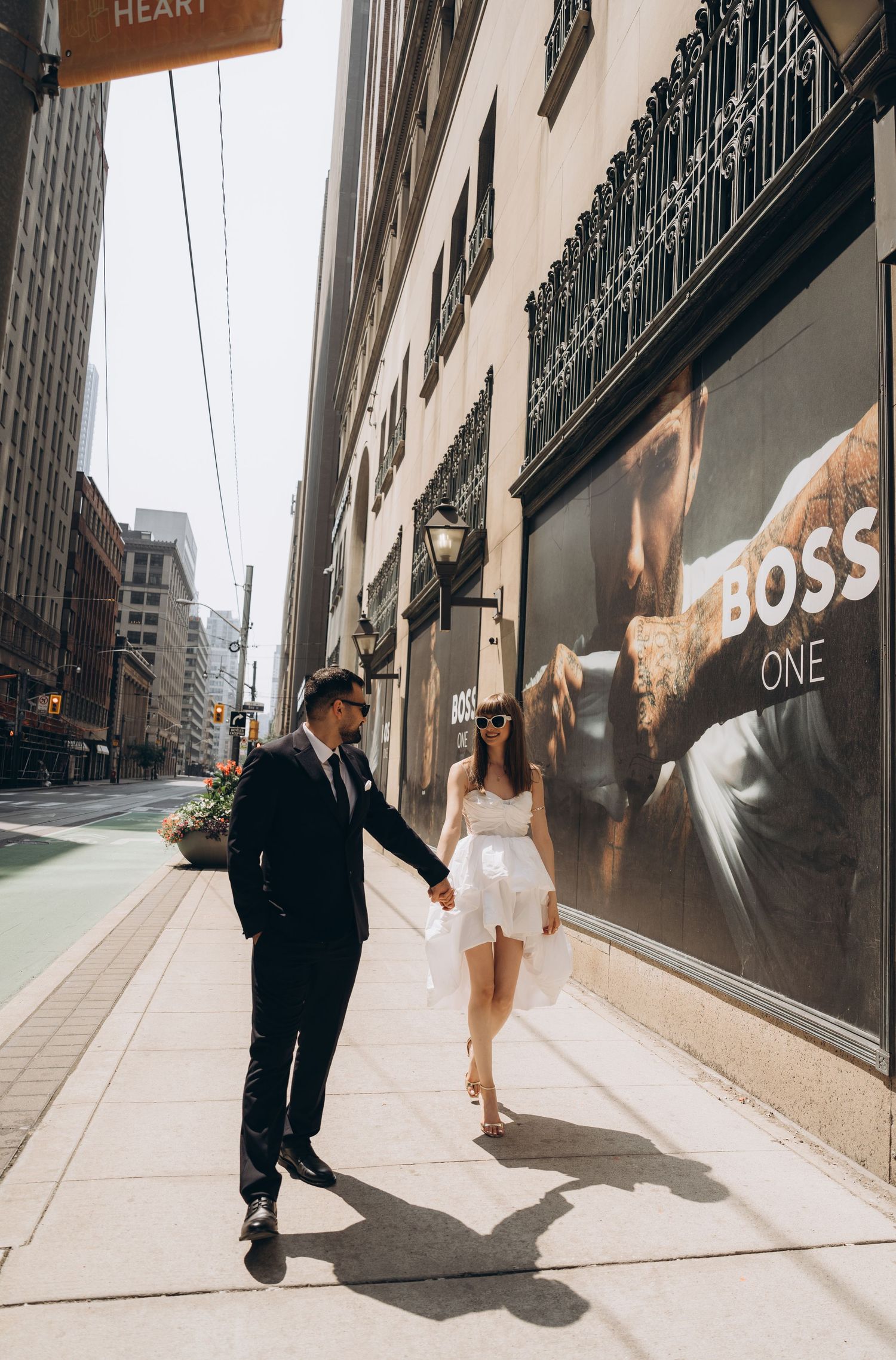 A split-screen sequence shows a couple walking down a city street with sunlight casting dramatic shadows against storefronts.