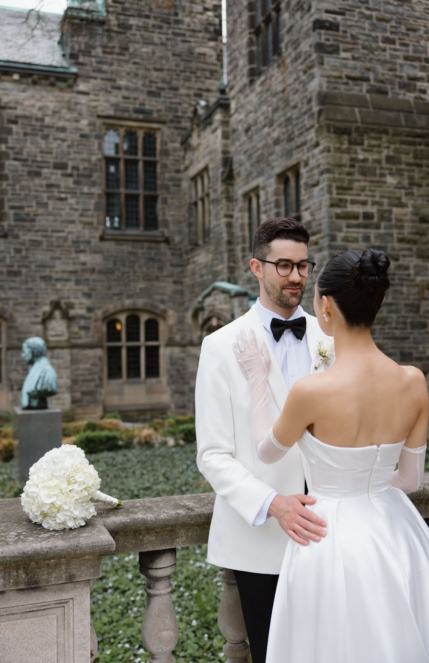 A tender wedding moment captured in sequence showing a couple in white attire embracing on stone steps of a historic building.