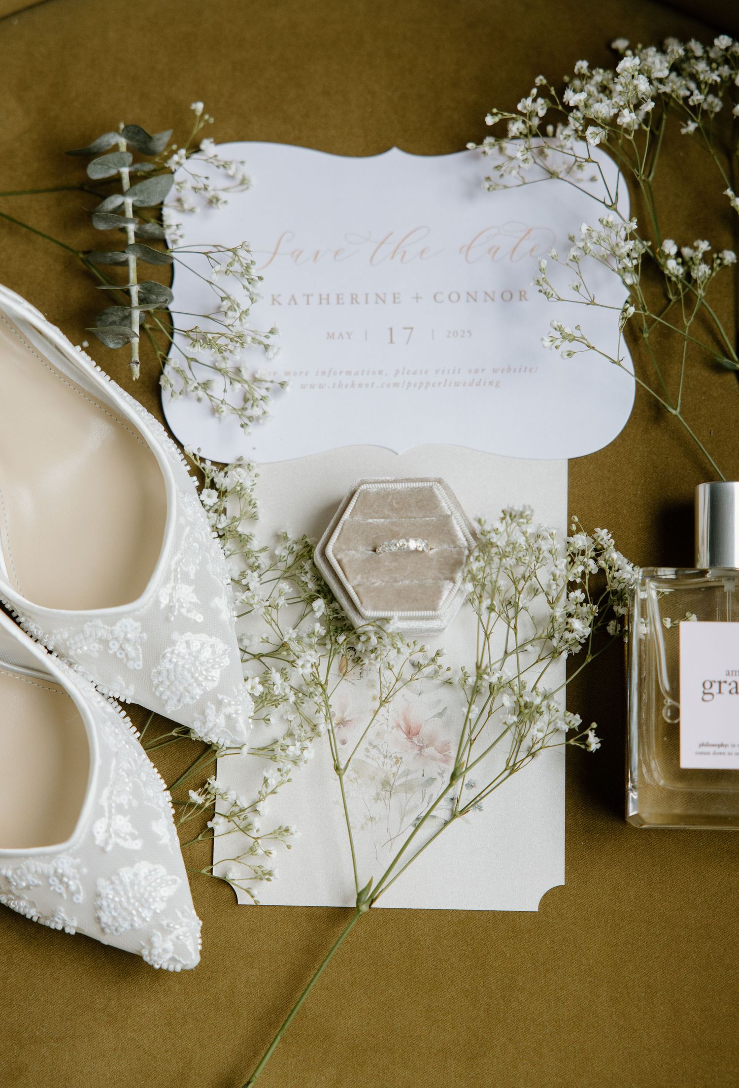 Wedding invitation suite with delicate baby's breath flowers and white stationery pieces arranged on brown paper background.