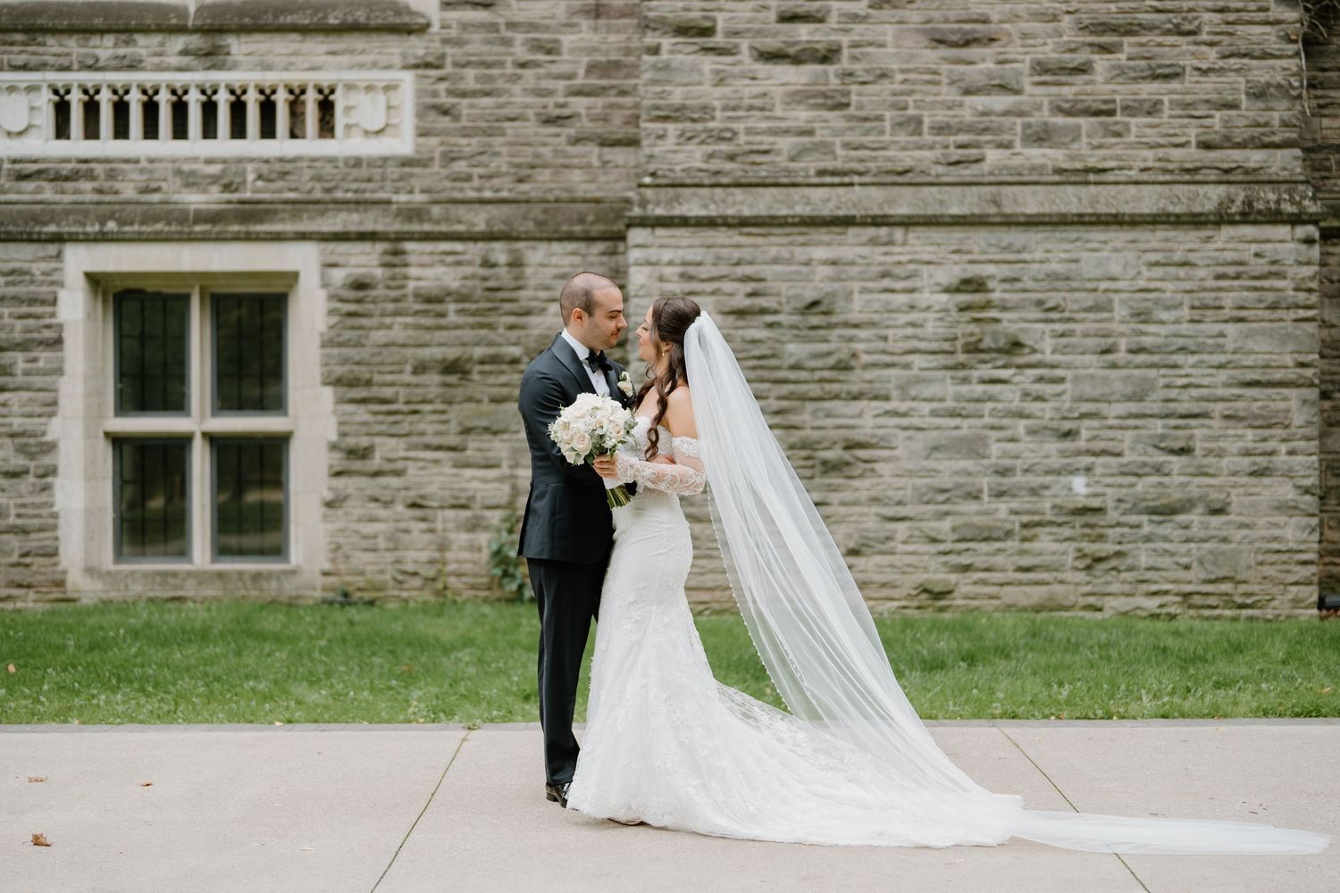 Bride and groom share romantic moments outside a stone building during their wedding photoshoot.