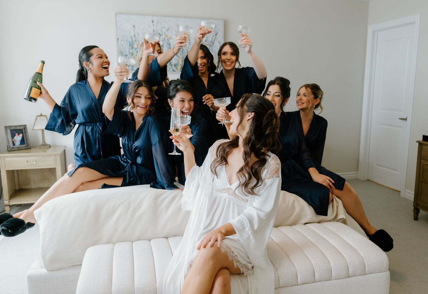 A group celebrates joyfully together while sitting and lounging on a white couch.
