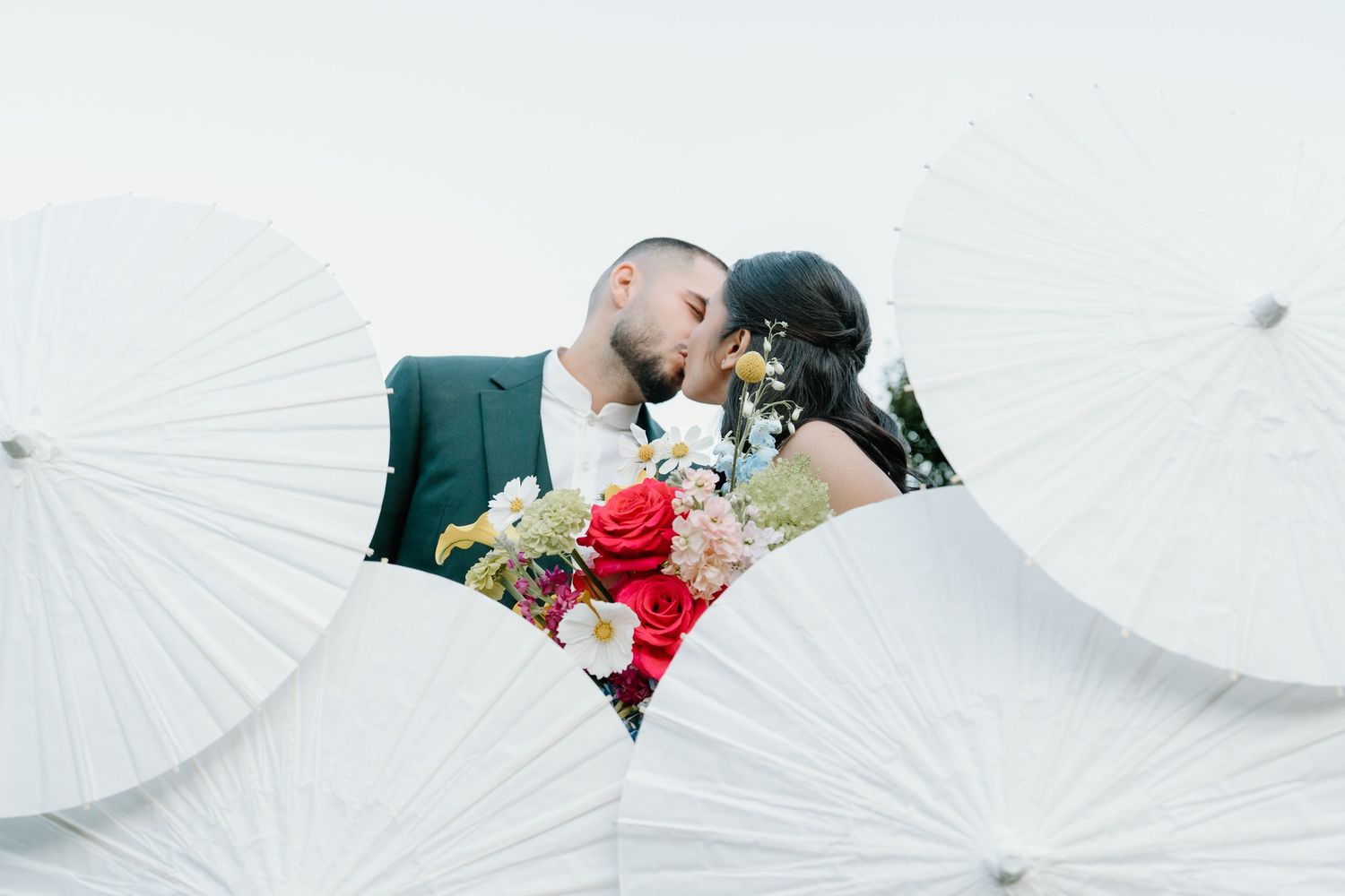 A white paper parasol is held against a bright background creating an elegant minimalist scene.