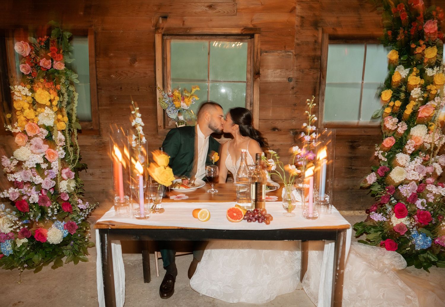 Wedding reception venue with rustic wood walls decorated with vibrant floral arrangements and elegant table settings.
