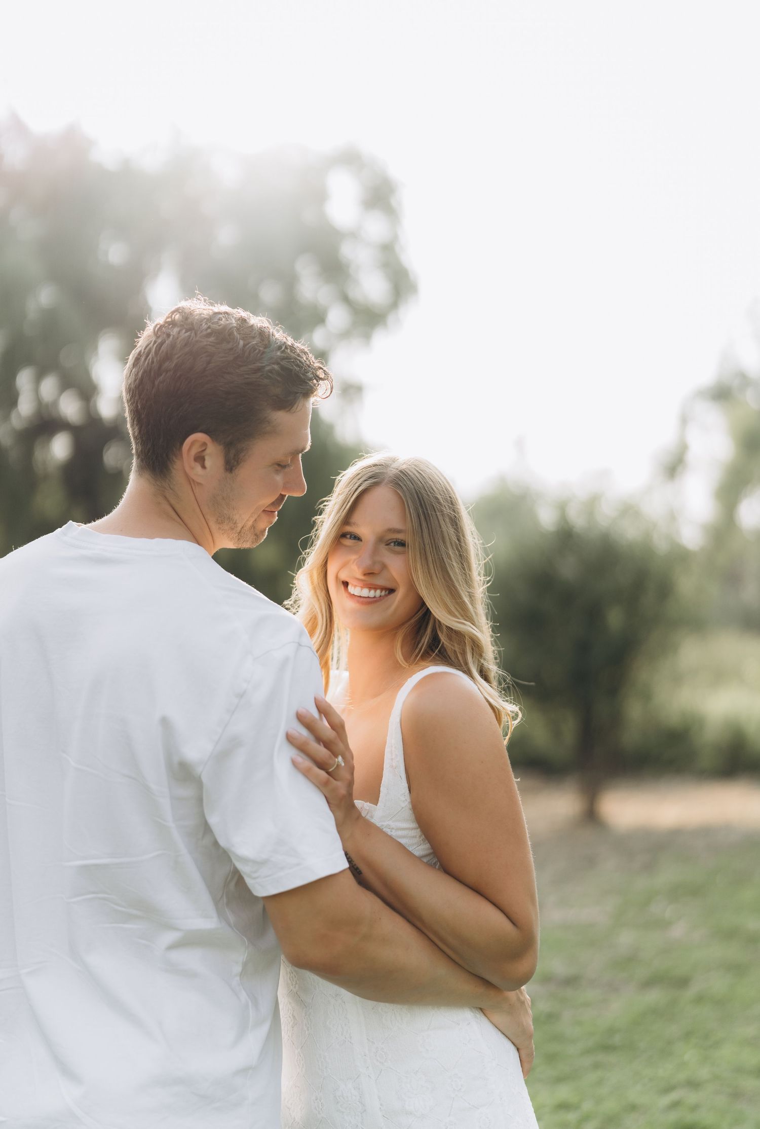 A romantic outdoor couple photoshoot with soft lighting and natural scenery in the background.