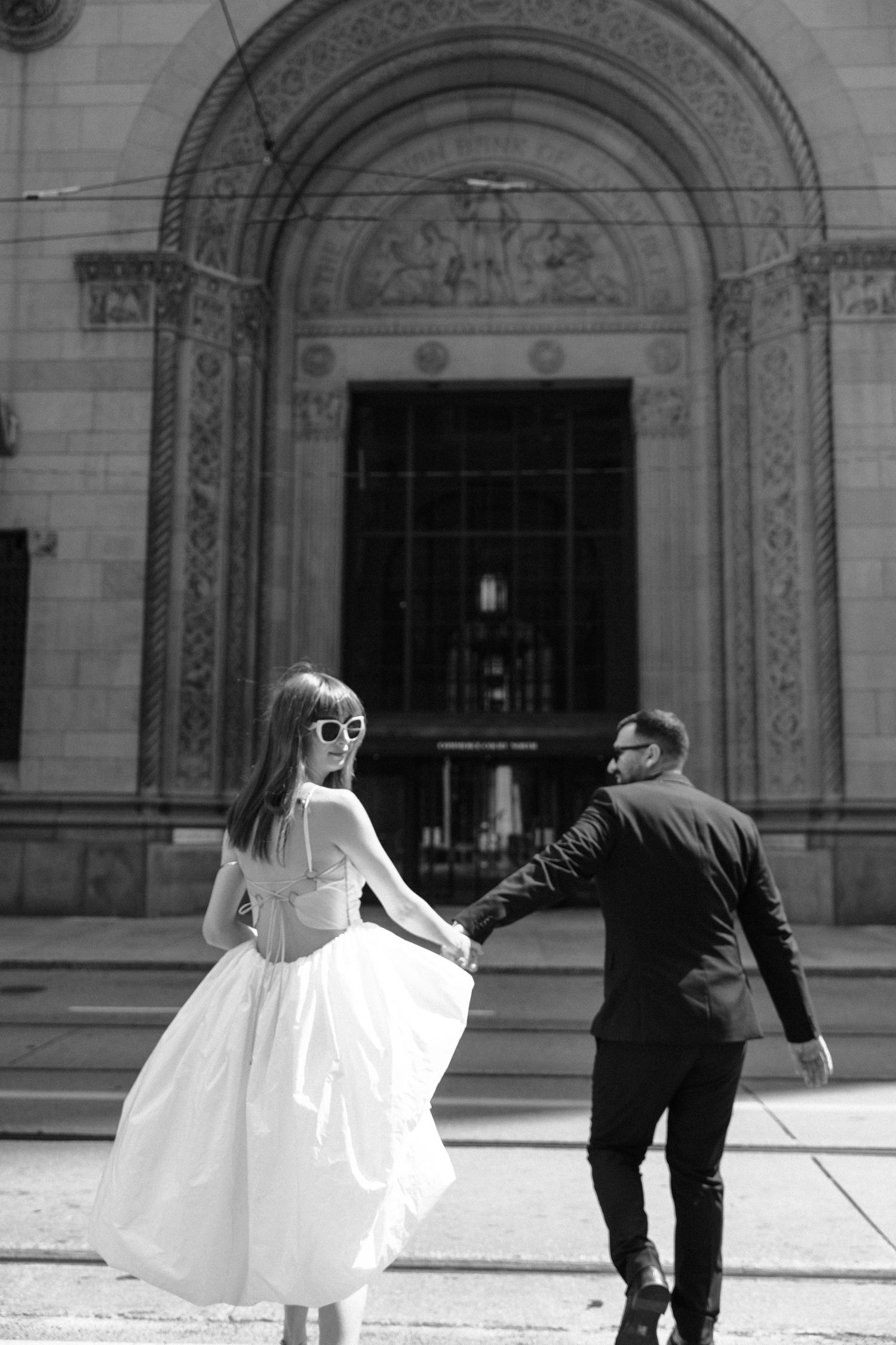 A bride's white wedding dress flows behind her as someone adjusts it in a sequence of black and white photos.