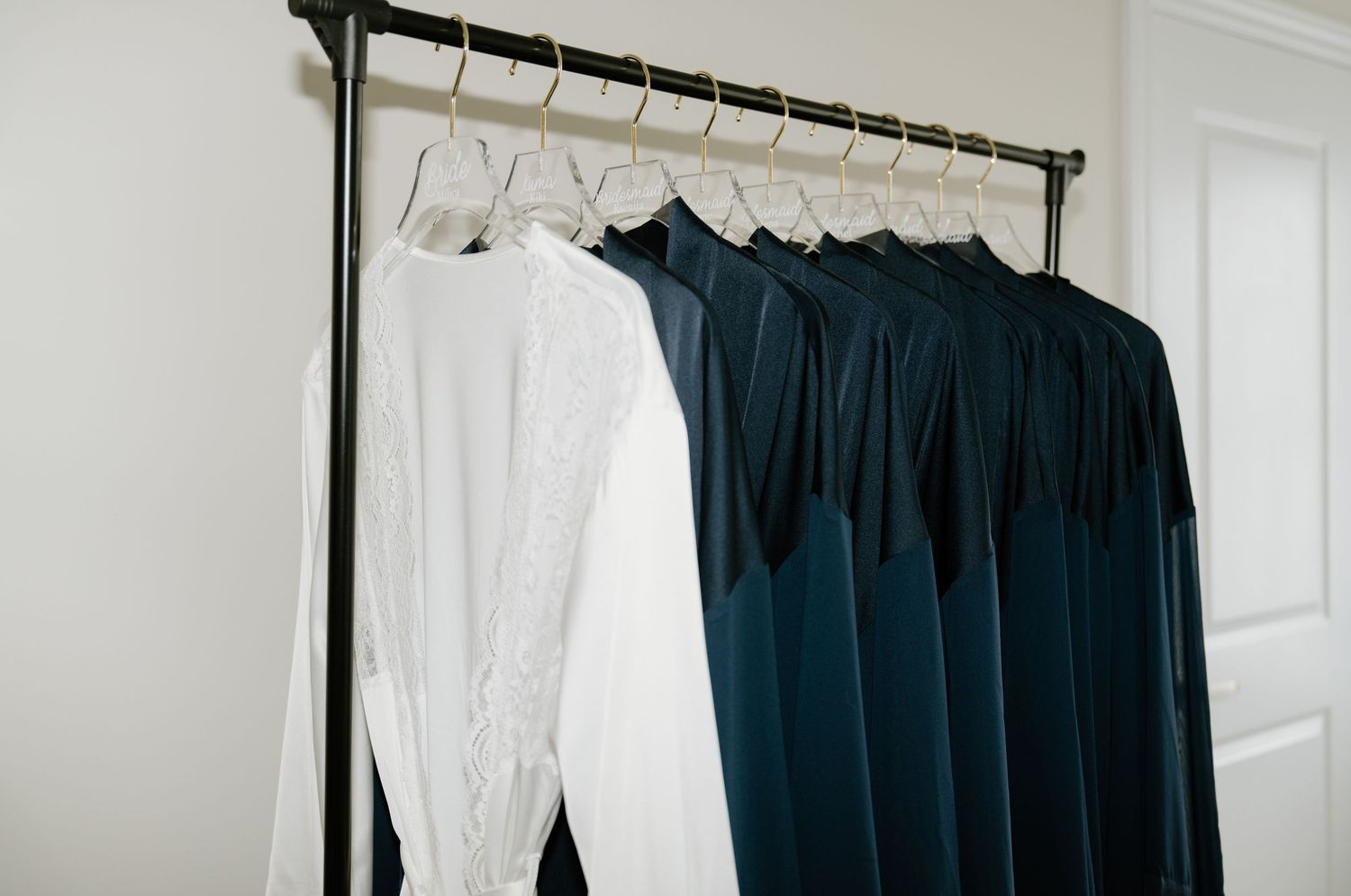 Black and white clothing hangs neatly on wooden hangers in a bright, organized closet space.