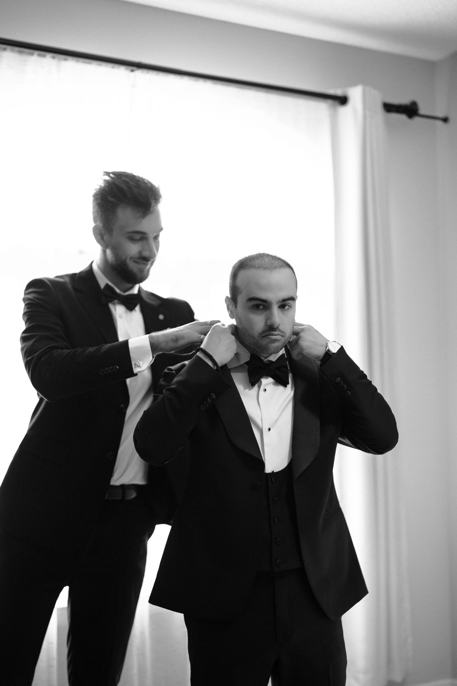 A sequence of black and white photos shows a person adjusting a formal black tuxedo and bowtie.