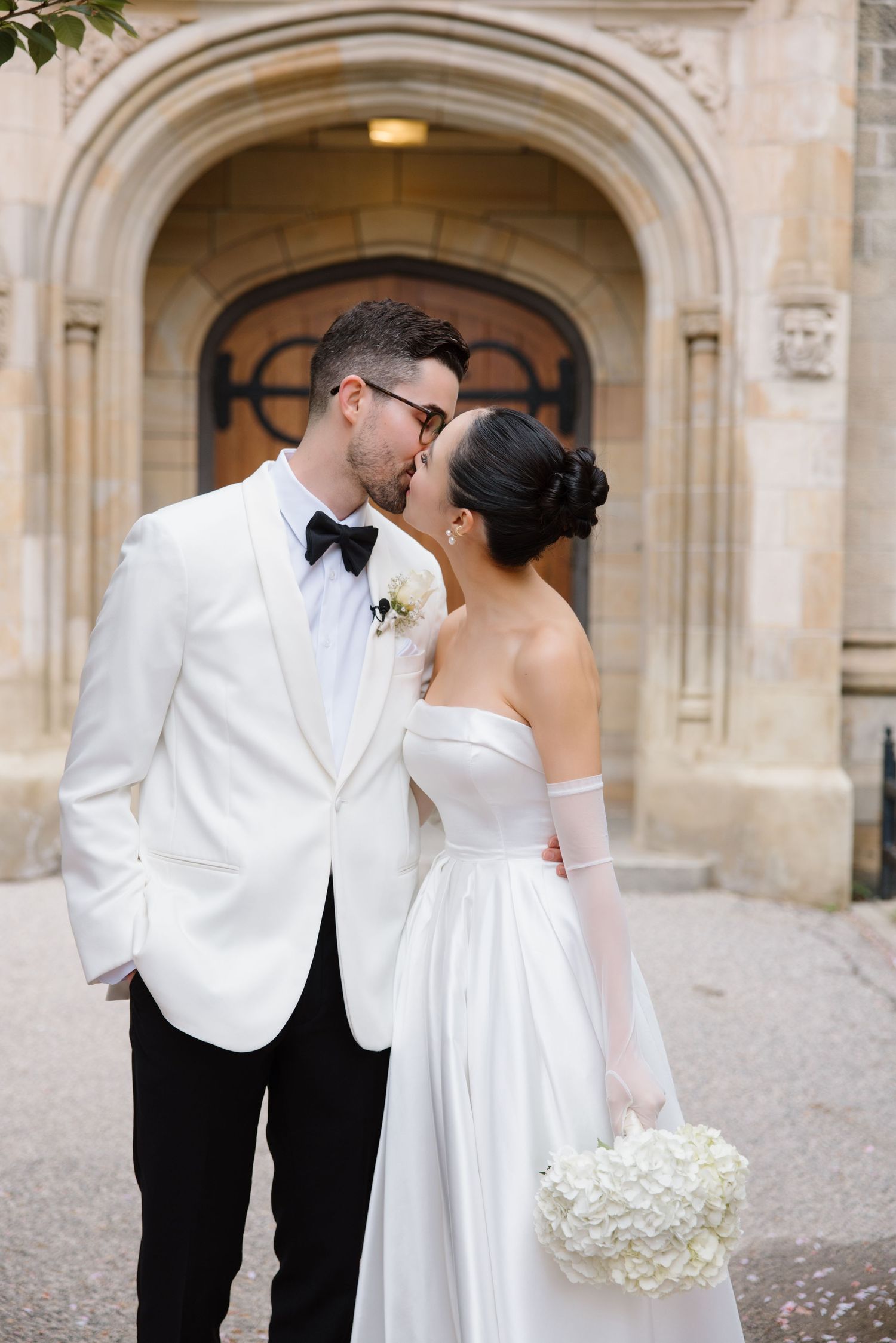 Bride and groom share romantic kisses in a series of elegant photos under stone archways of a historic building.