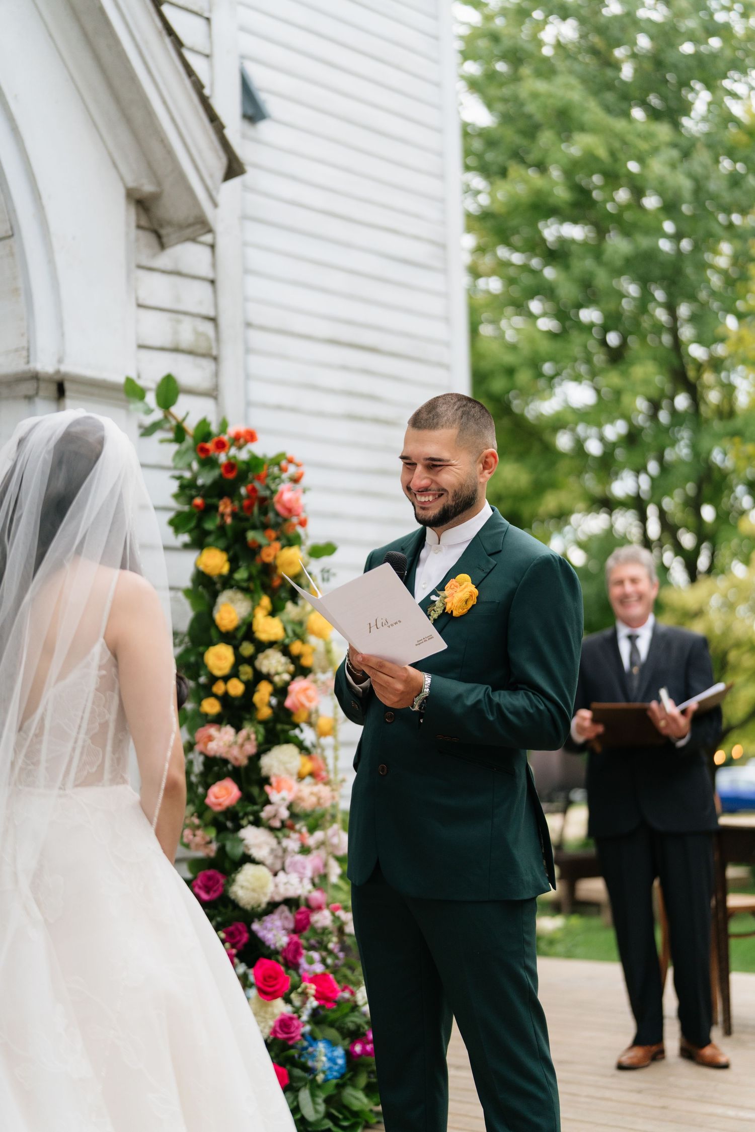 First look moment at a white chapel with beautiful floral decorations and Gothic architecture.