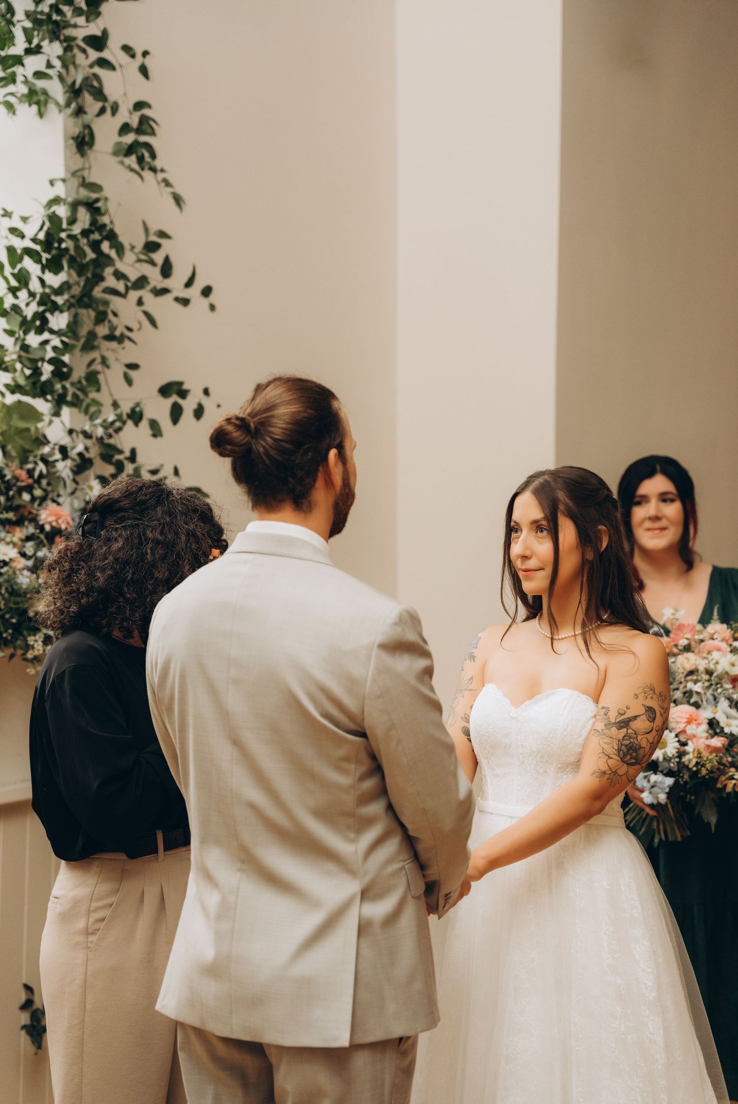 A series of wedding photos showing a couple in white dress and tan suit dancing together against a floral backdrop.