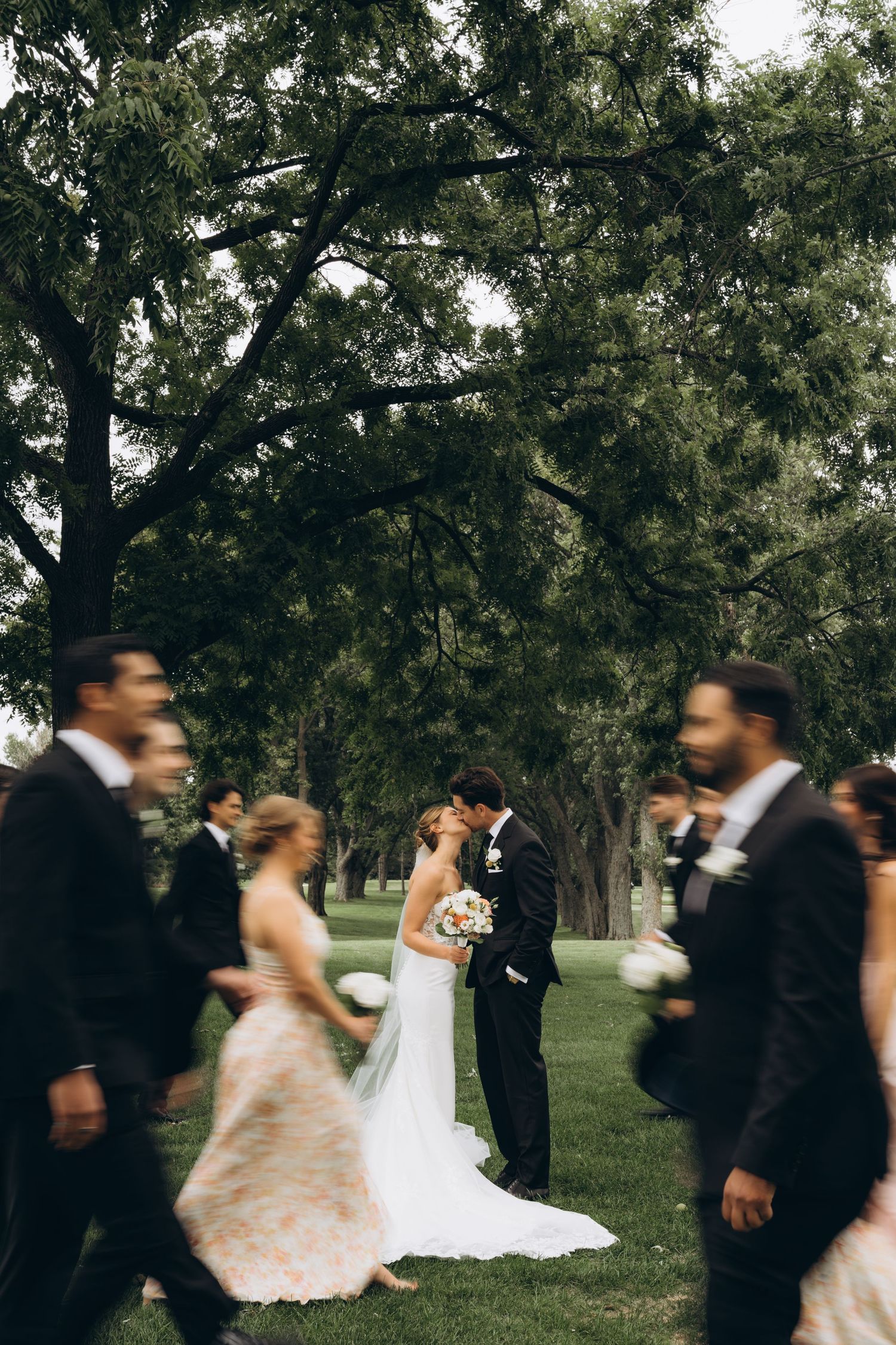 A sequence of motion-blurred wedding party photos showing couples dancing and spinning in a park setting.