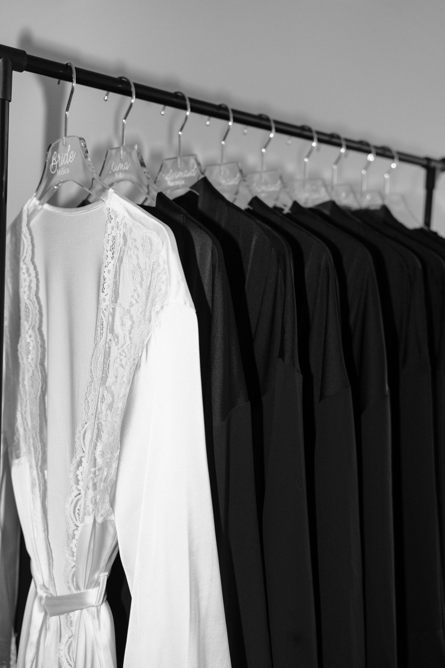 Black and white clothing hangs on a clothing rack, with white dresses and dark garments arranged in a row.