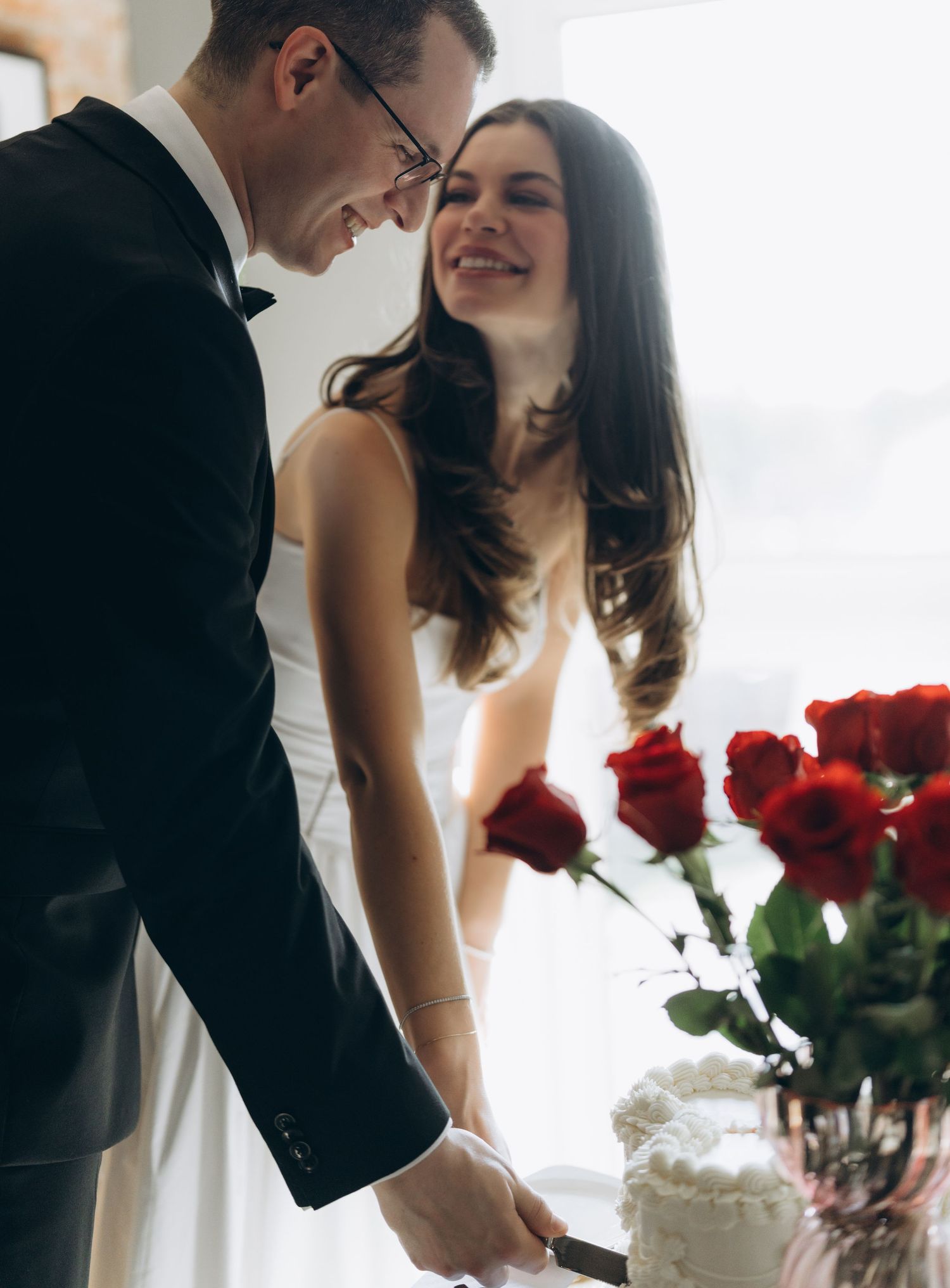 Romantic bride and groom share intimate moments with red roses in a series of candid wedding photographs.