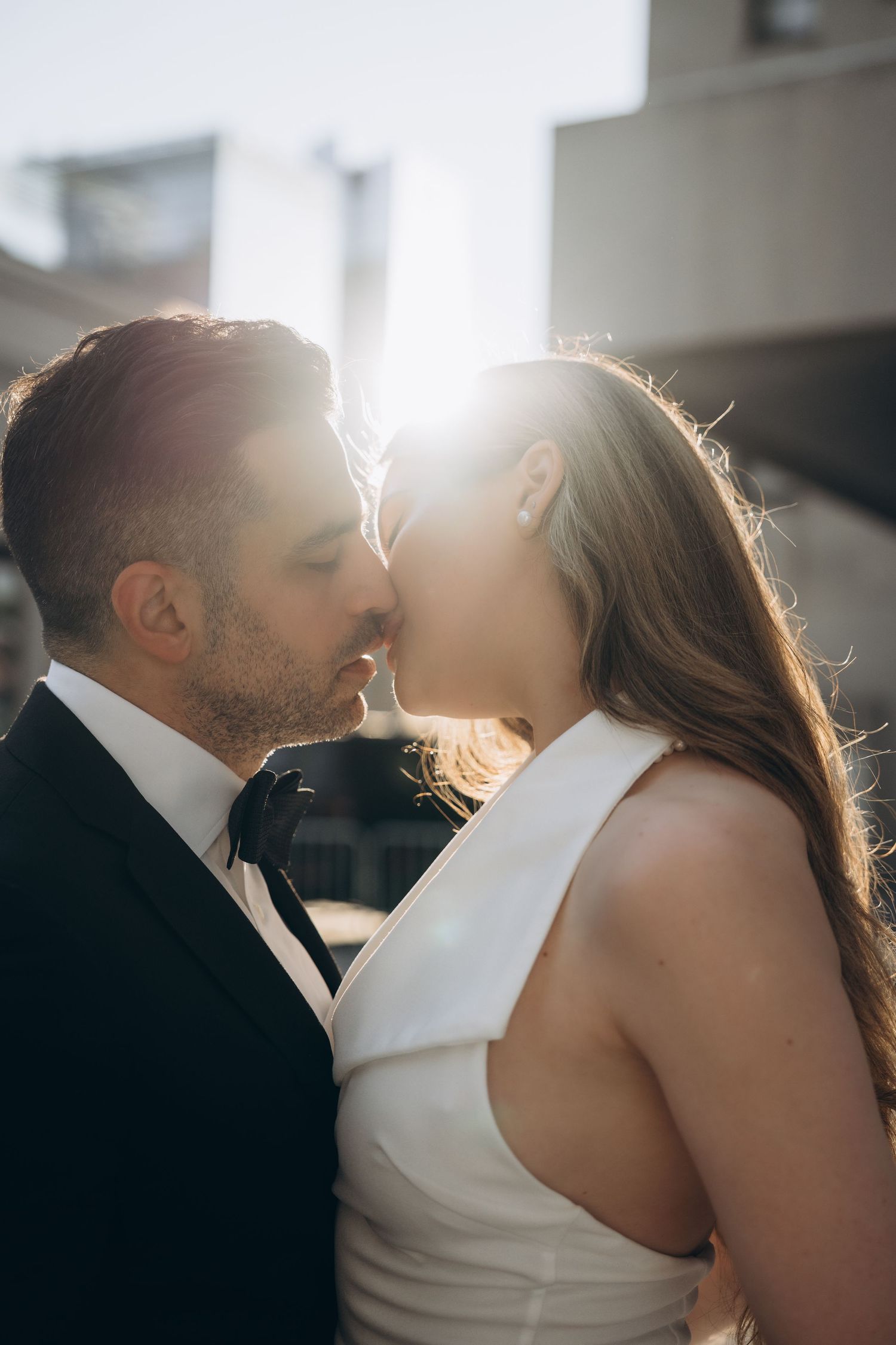 Close-up side profile silhouettes create an intimate romantic moment in warm natural light.