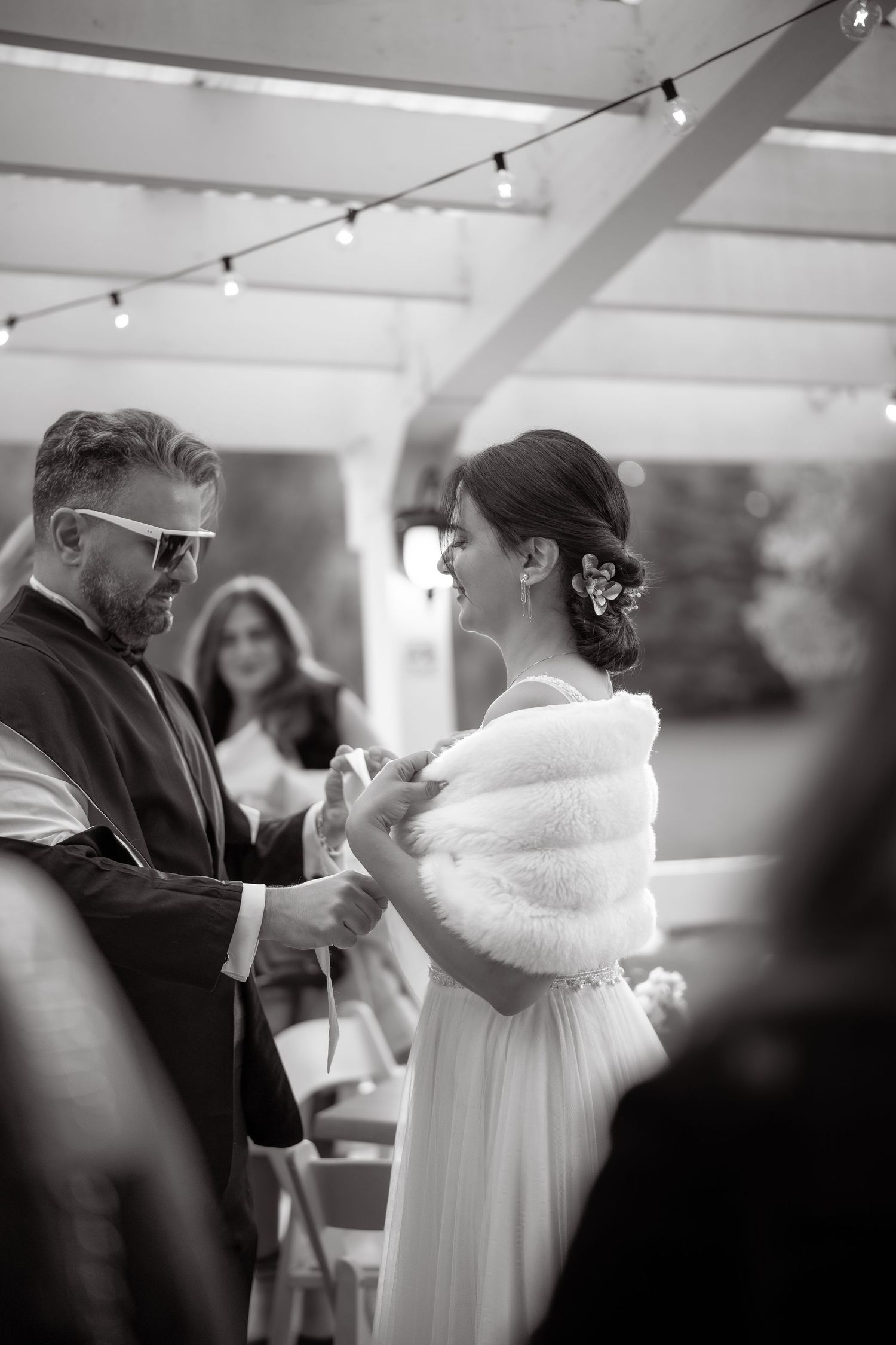 A wedding couple shares a tender moment during their reception under string lights.