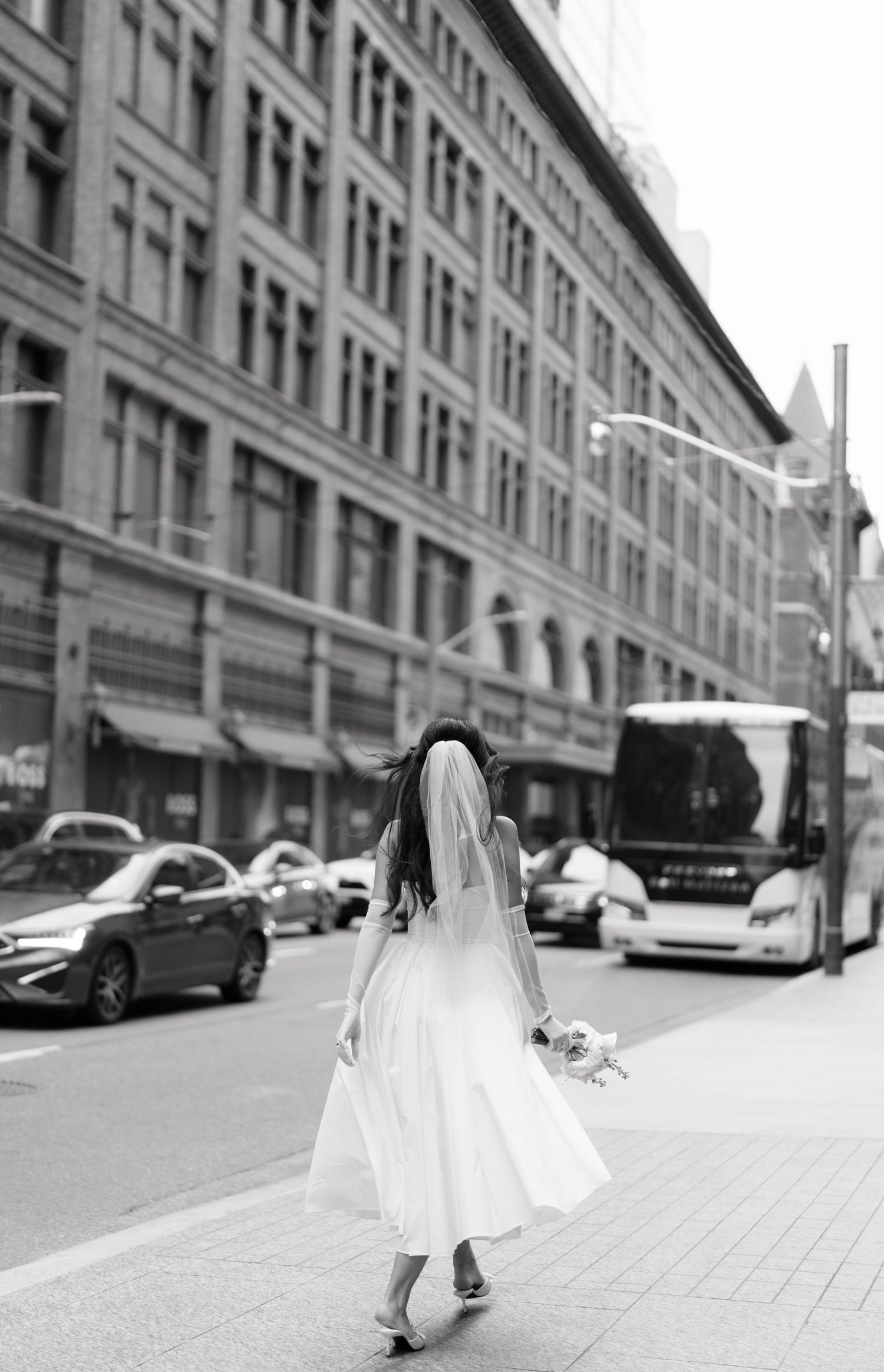 A black and white composite photo sequence shows a person in a white dress walking along an urban street with buildings.