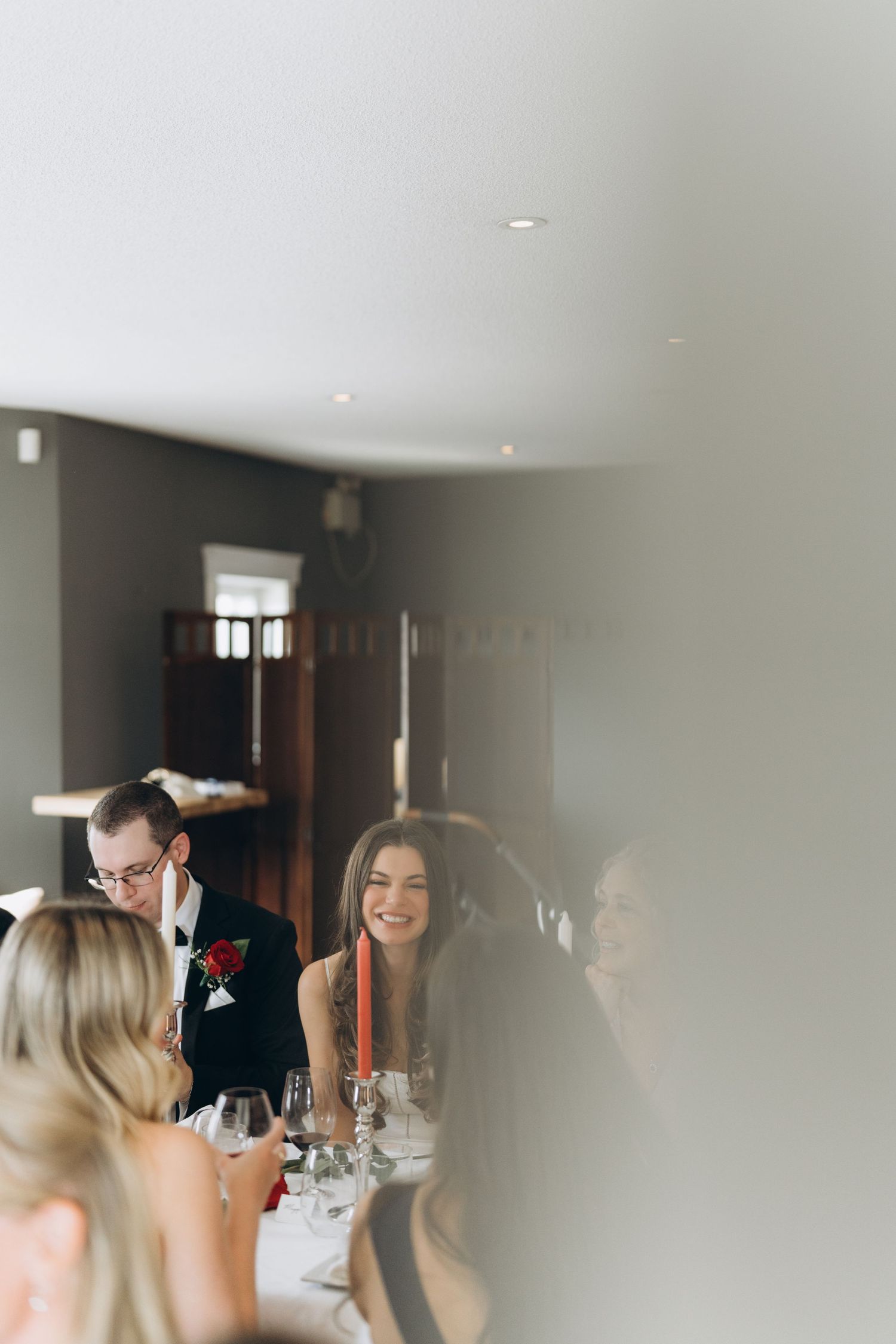 Wedding reception guests gather around a table for conversation and celebration inside an elegant venue.