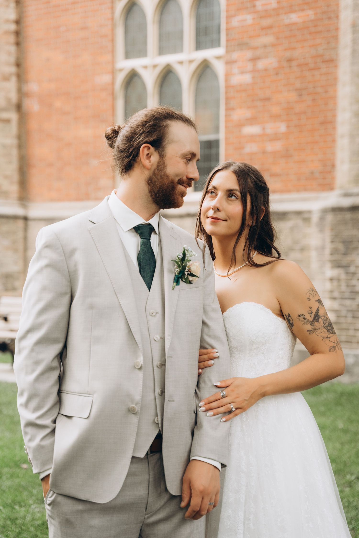 A romantic wedding couple shares intimate moments together against a brick building backdrop.
