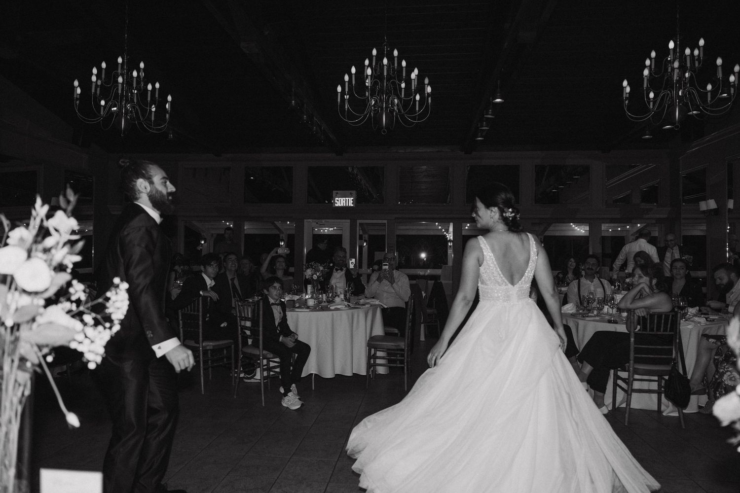 Black and white capture of wedding dress twirling during first dance at reception.