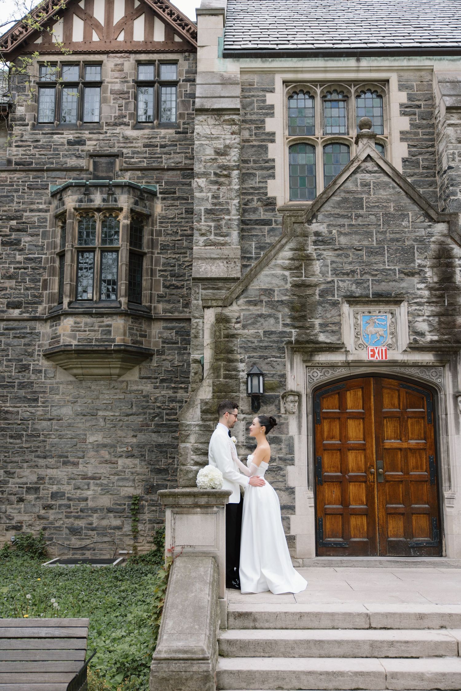 Gothic stone building with Tudor-style architecture featuring a grand wooden entrance doorway and ornate windows.