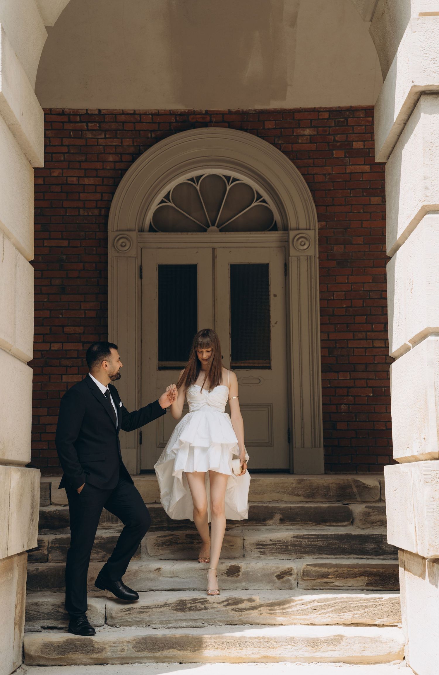 Split panoramic wedding photo showing repeating columns and archways at a brick building entrance.